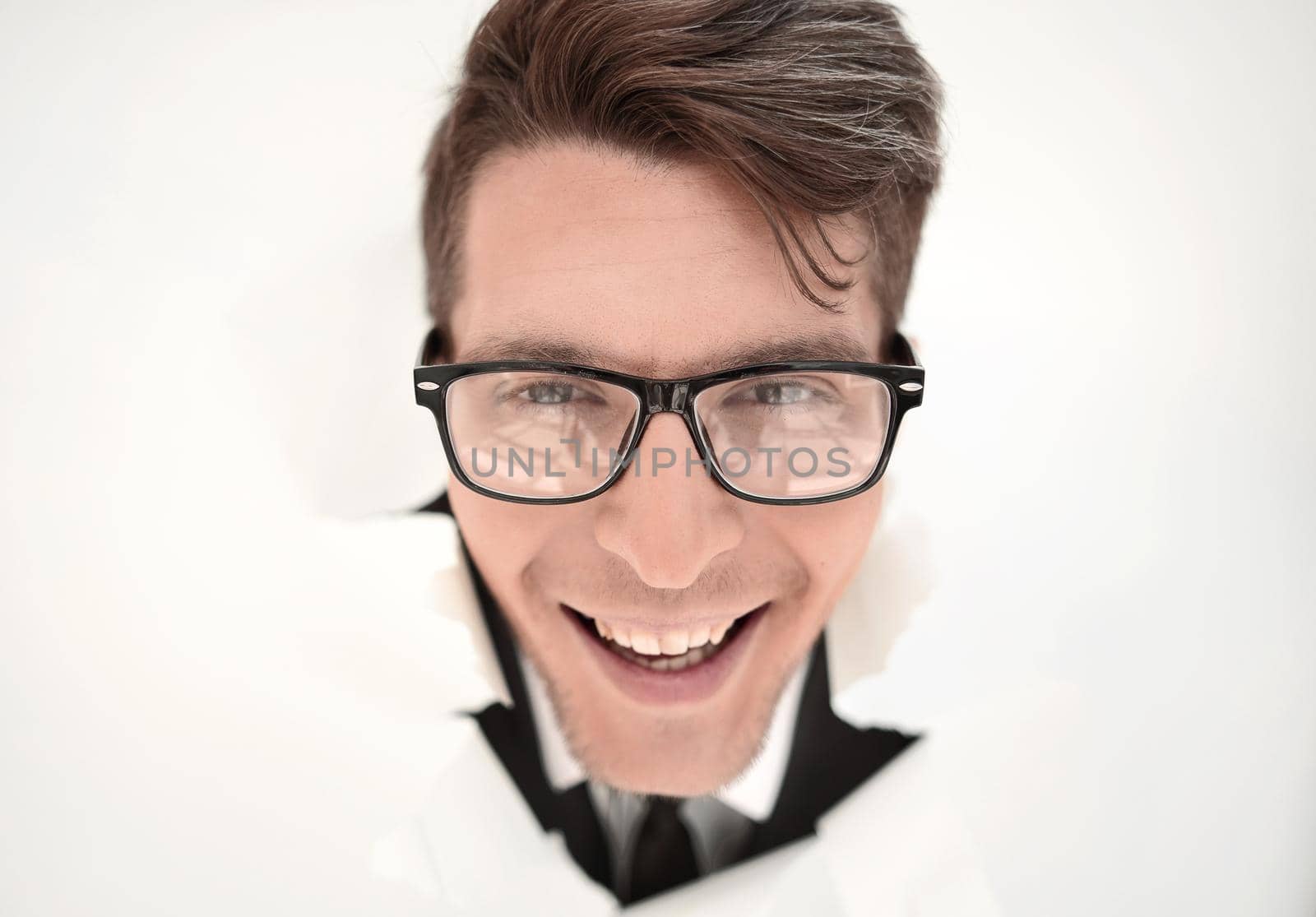 young businessman breaking through a white paper wall.photo with copy space