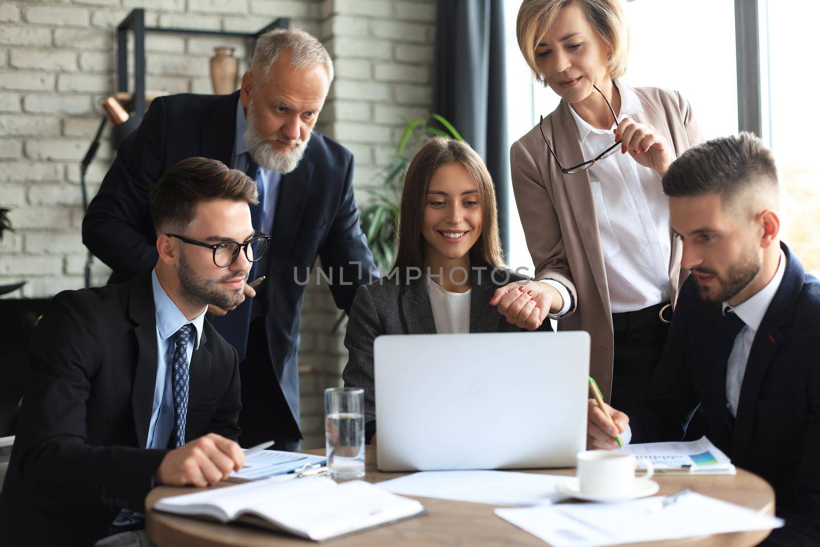 Startup business team on meeting in modern bright office interior and working on laptop