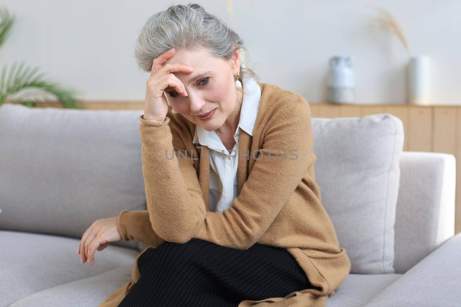Worried middle aged woman sitting on a sofa in the living room