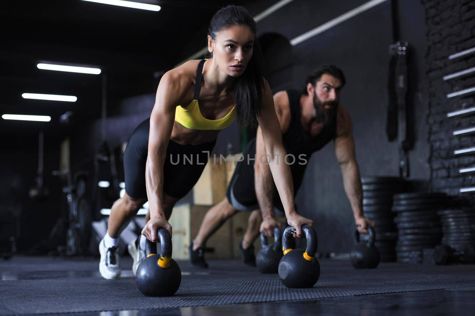 Sporty indian man and woman doing push-up in a gym. by tsyhun