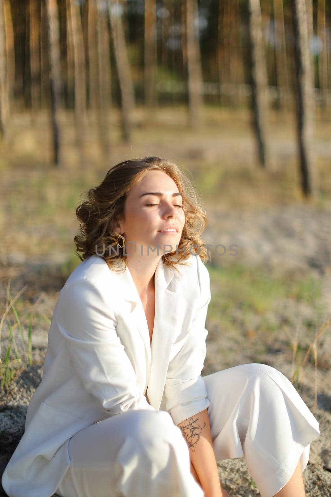 Young nice woman sitting on sand beach with trees in background. by sisterspro