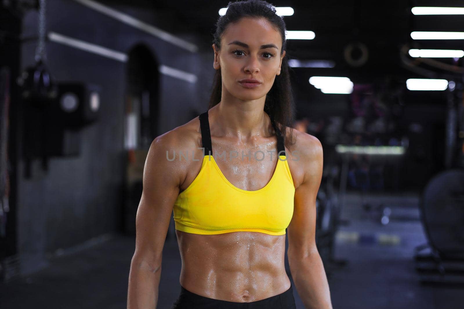 Muscular fit woman standing in gym, looking at camera