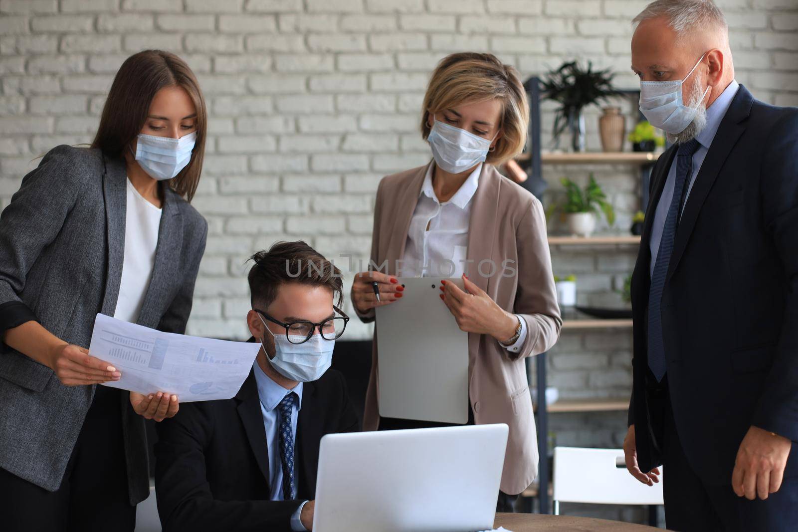 Business team in protective masks works in the office. by tsyhun
