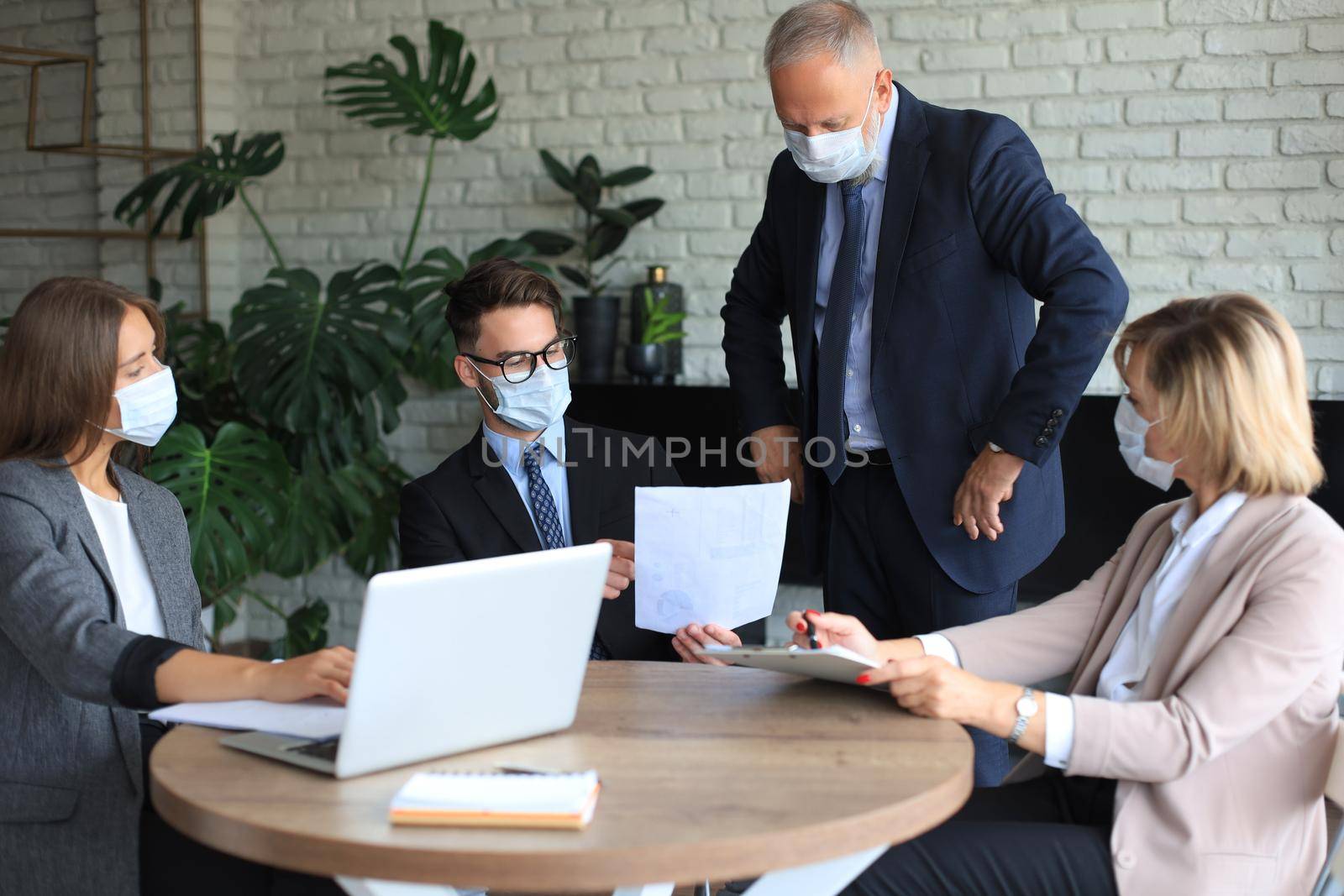 Business team in protective masks works in the office. by tsyhun