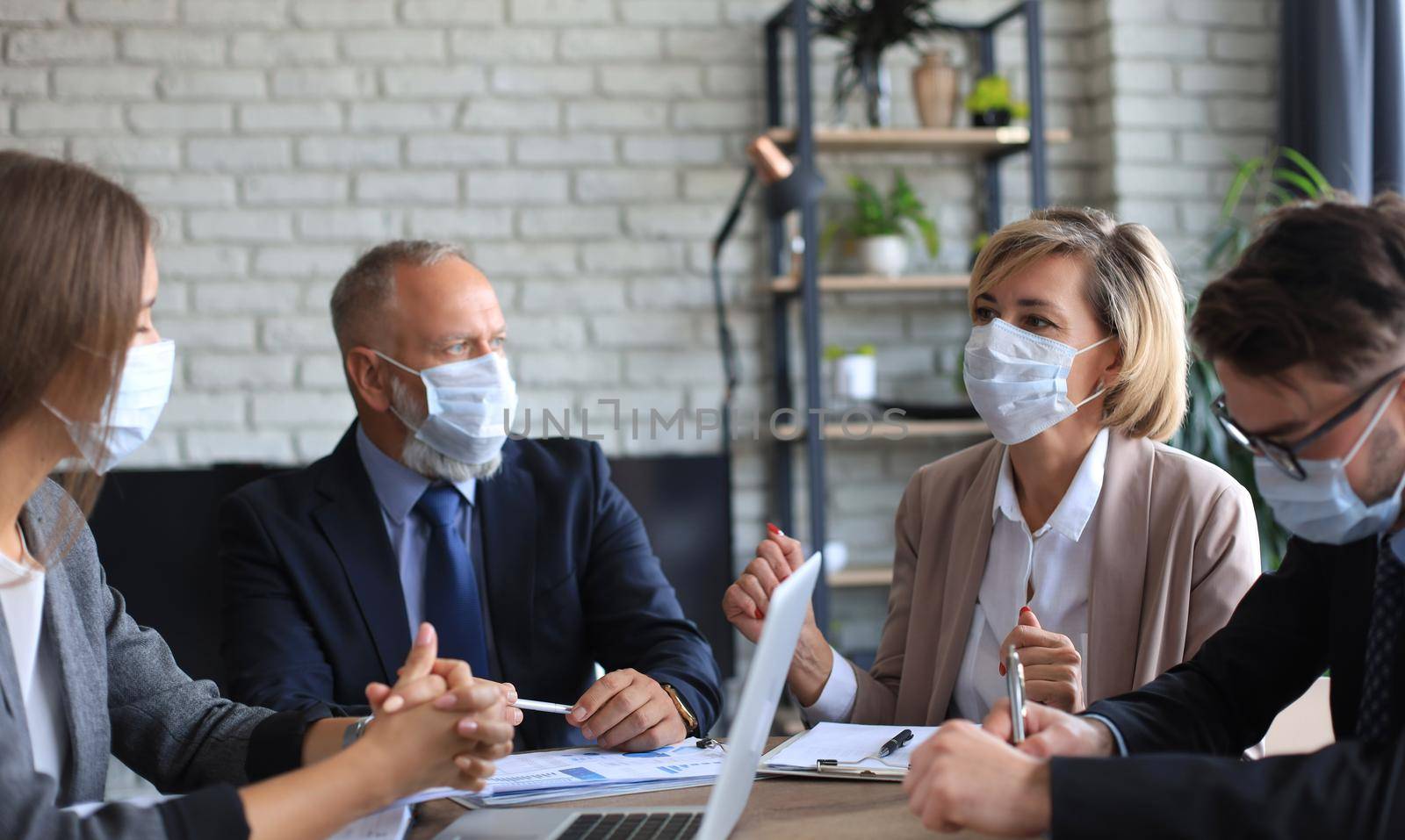 Business people wearing protective face masks while holding a presentation on a meeting during coronavirus epidemic