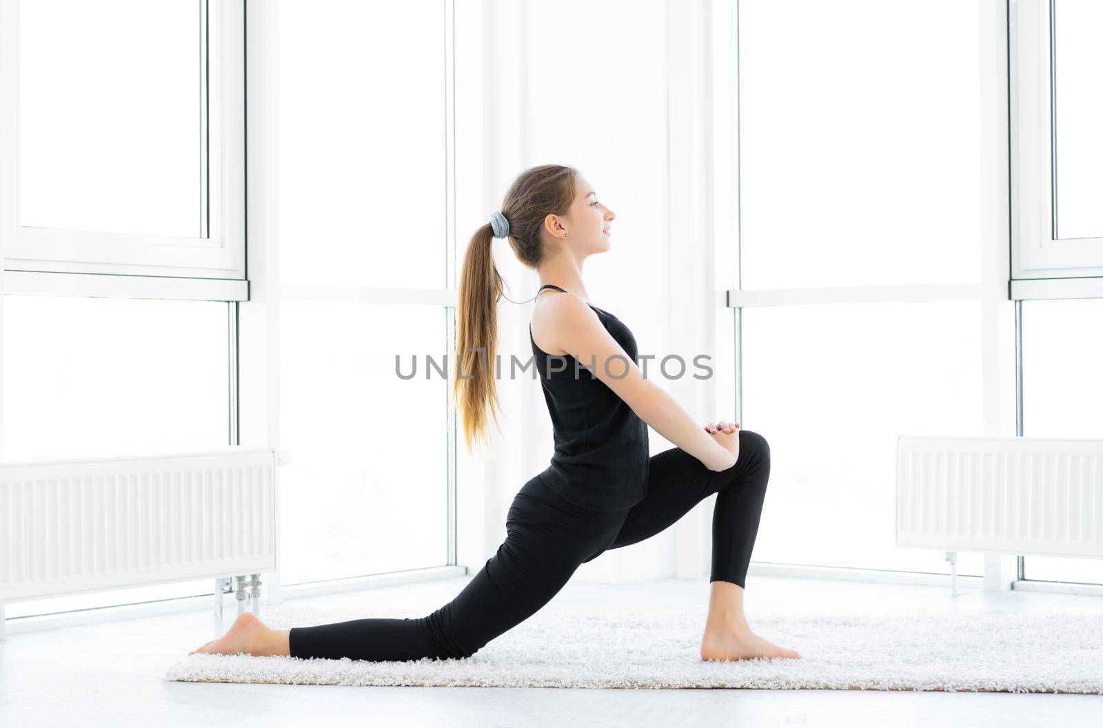 Cute girl doing lunges exercise in light room