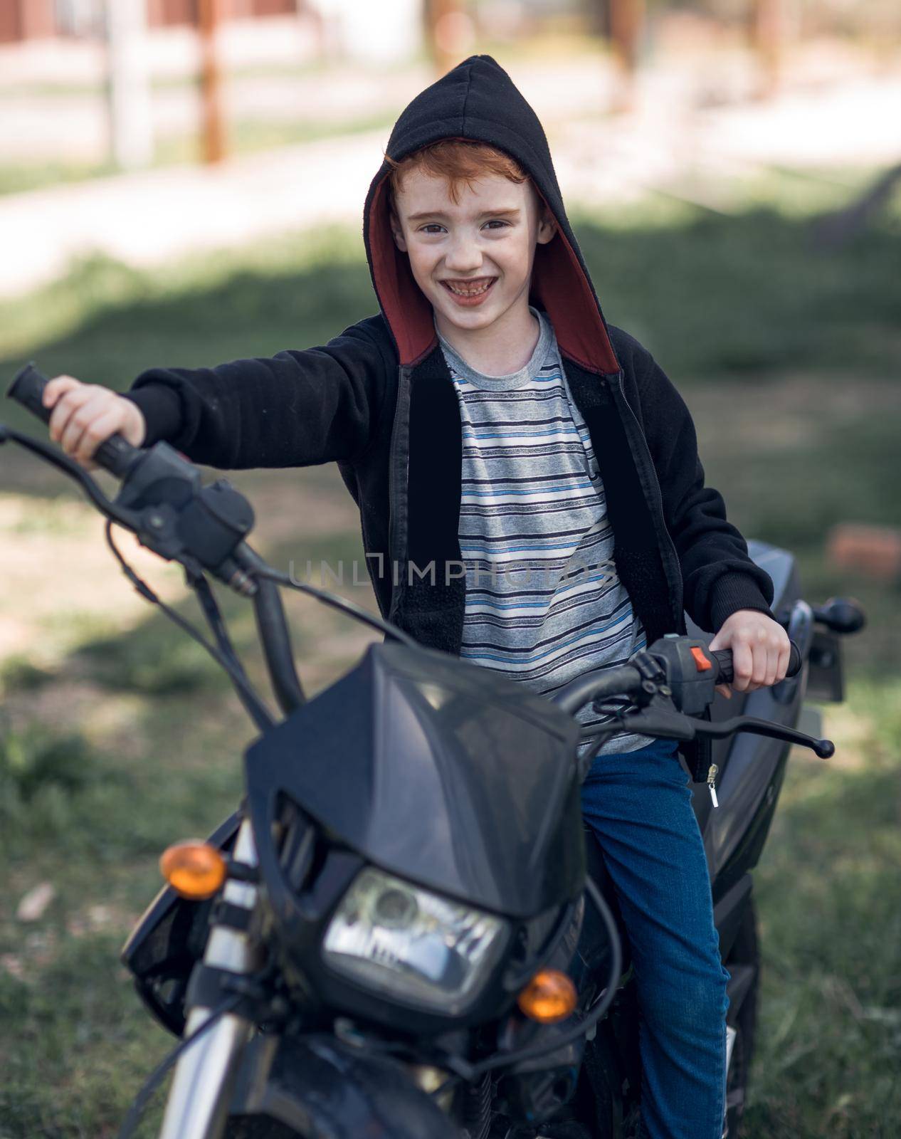 smiling little biker riding a motorcycle as a symbol of adventure and travel