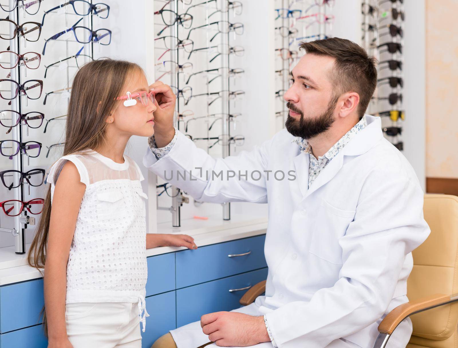 Little girl and doctor ophthalmologist choose glasses