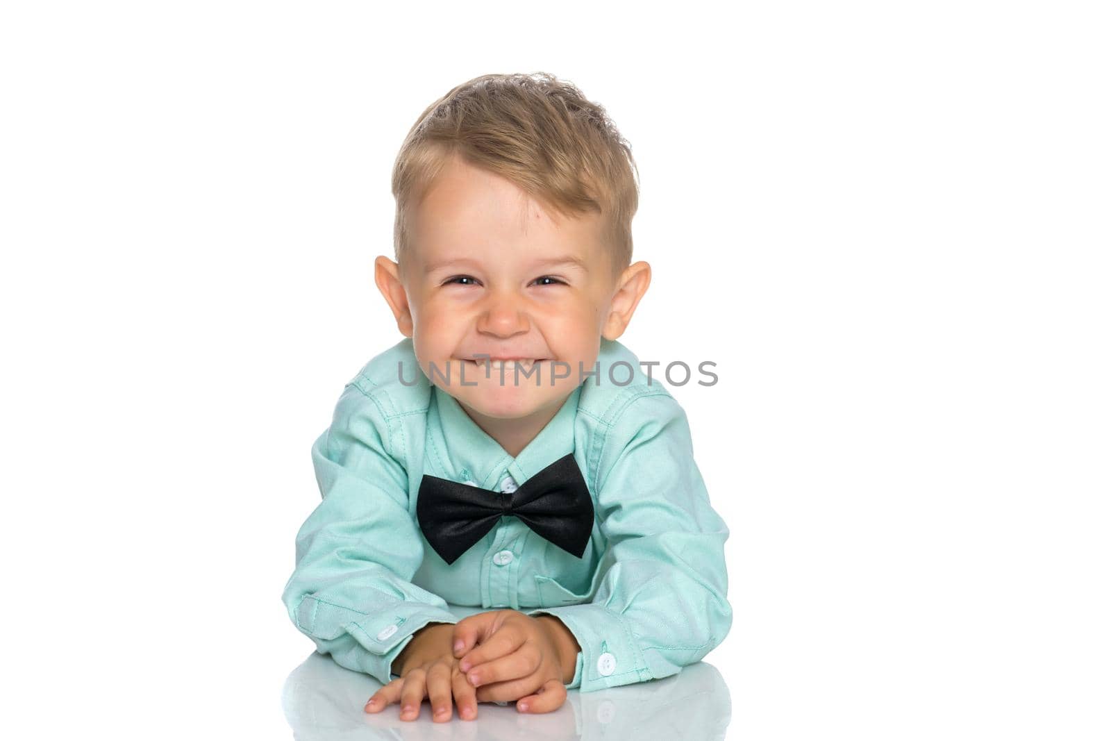 Little boy is lying on the floor in the studio on a white background. The concept of a happy childhood, a child in the family. Isolated.
