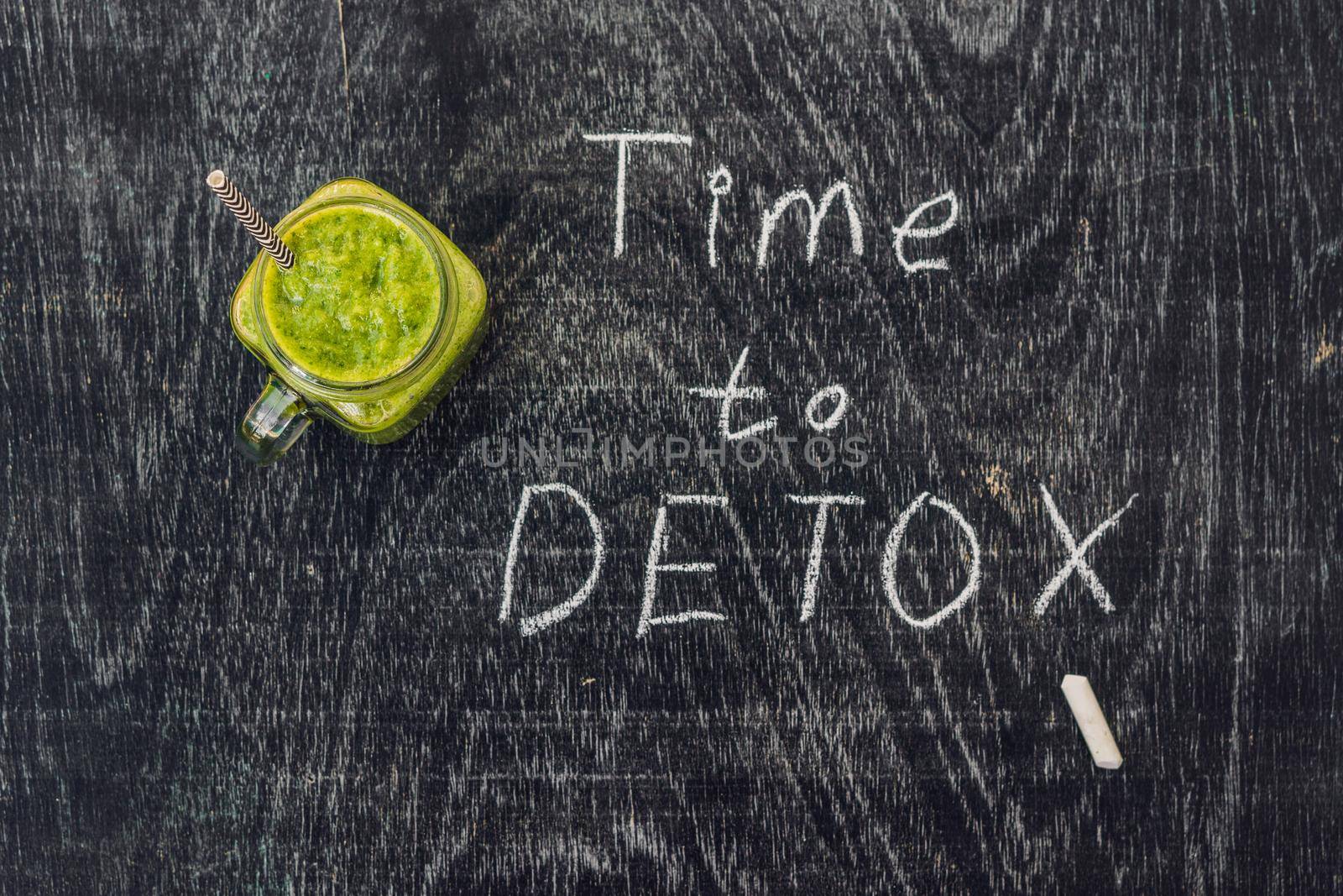 TIME TO DETOX chalk inscription on the wooden table and Green smoothies made of spinach. Healthy eating and sports concept by galitskaya