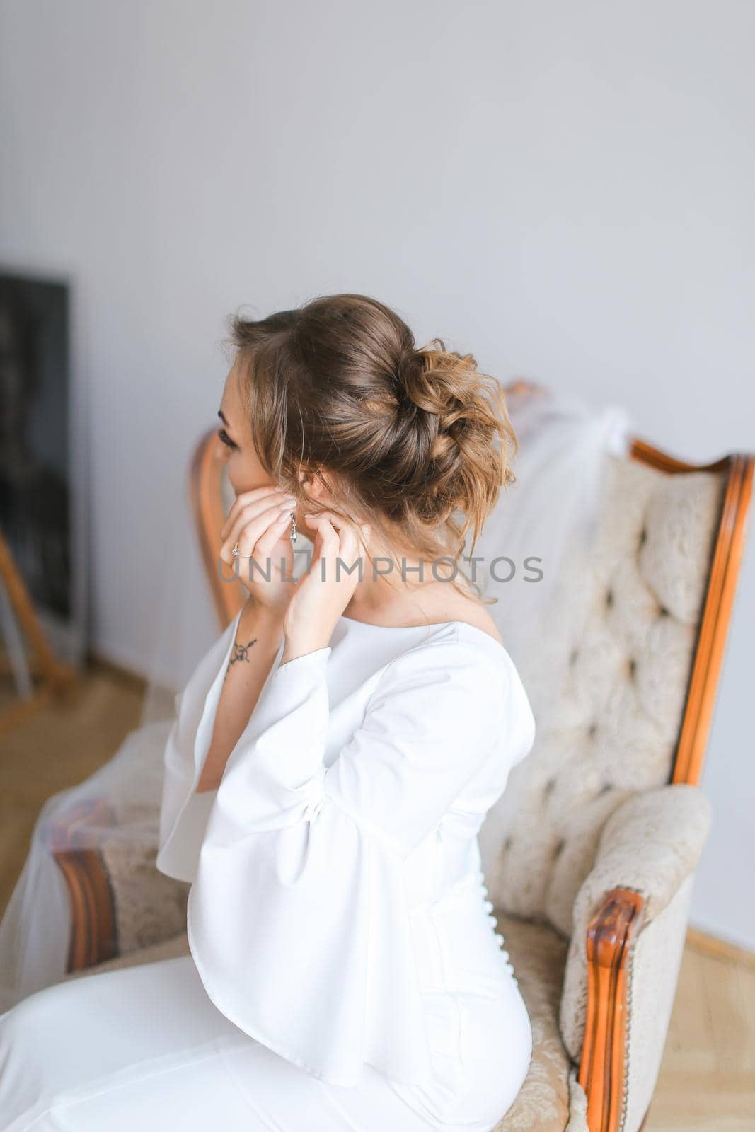 Young bride dressing earrings. Concept of wedding preparing in morning.