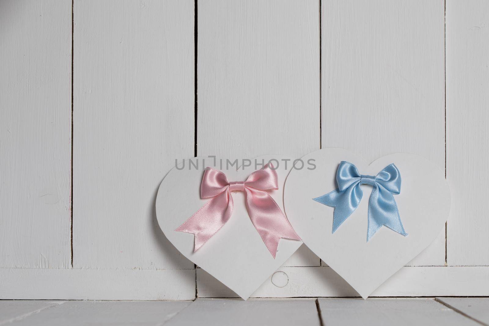 Valentines Day ornate heart shaped cards with pink and blue ribbon bows on white wooden background with copy space for text