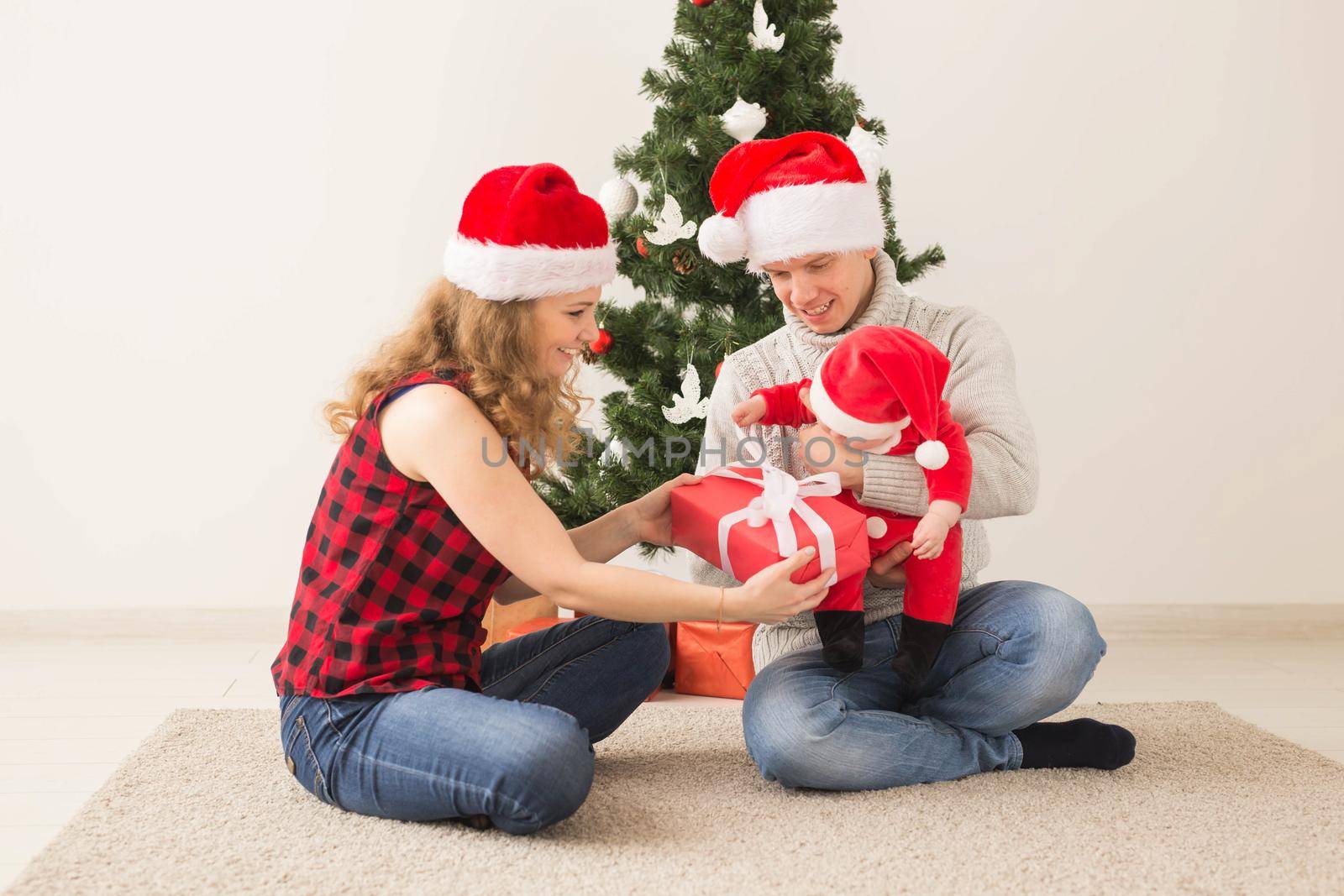 Happy couple with baby celebrating Christmas together at home