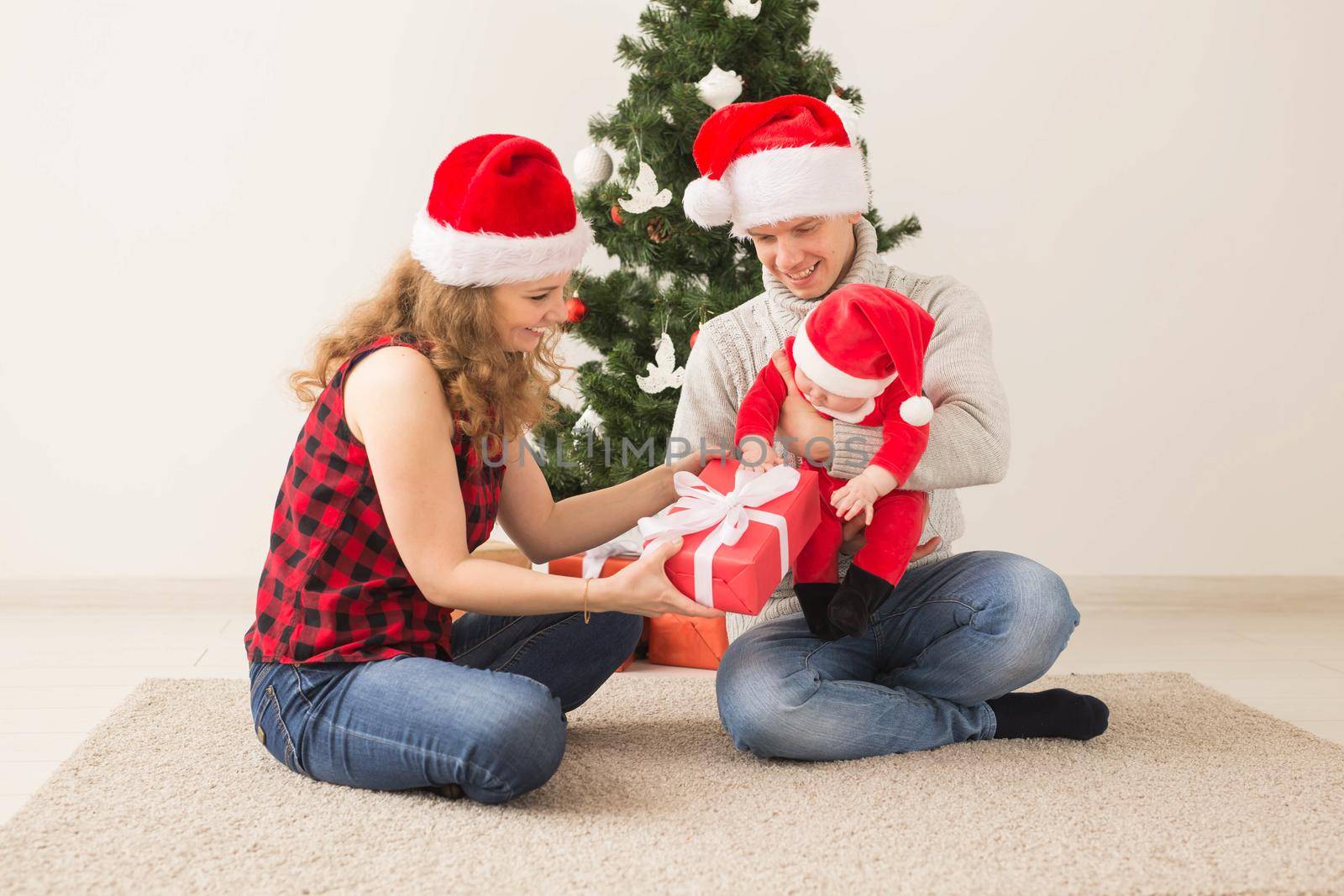 Holidays, children and family concept - Happy couple with baby celebrating Christmas together at home