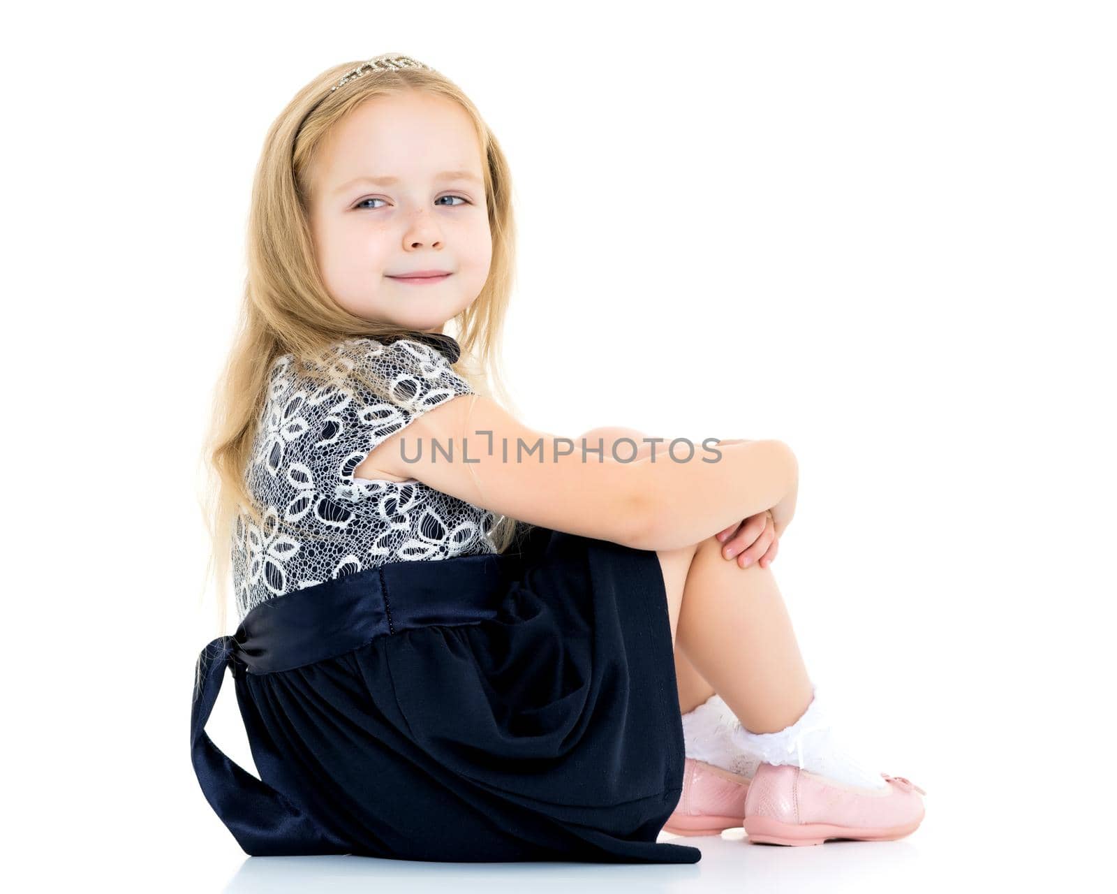 Little girl is sitting on the floor. The concept of a happy childhood. Isolated on white background.