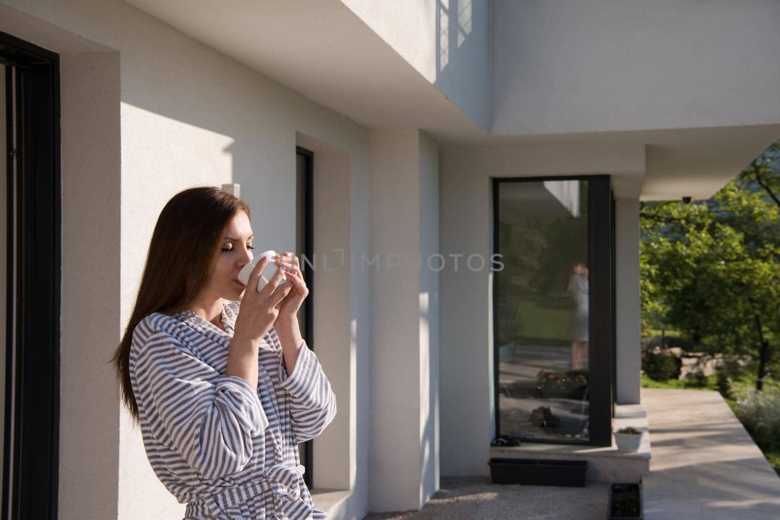 woman in a bathrobe enjoying morning coffee by dotshock