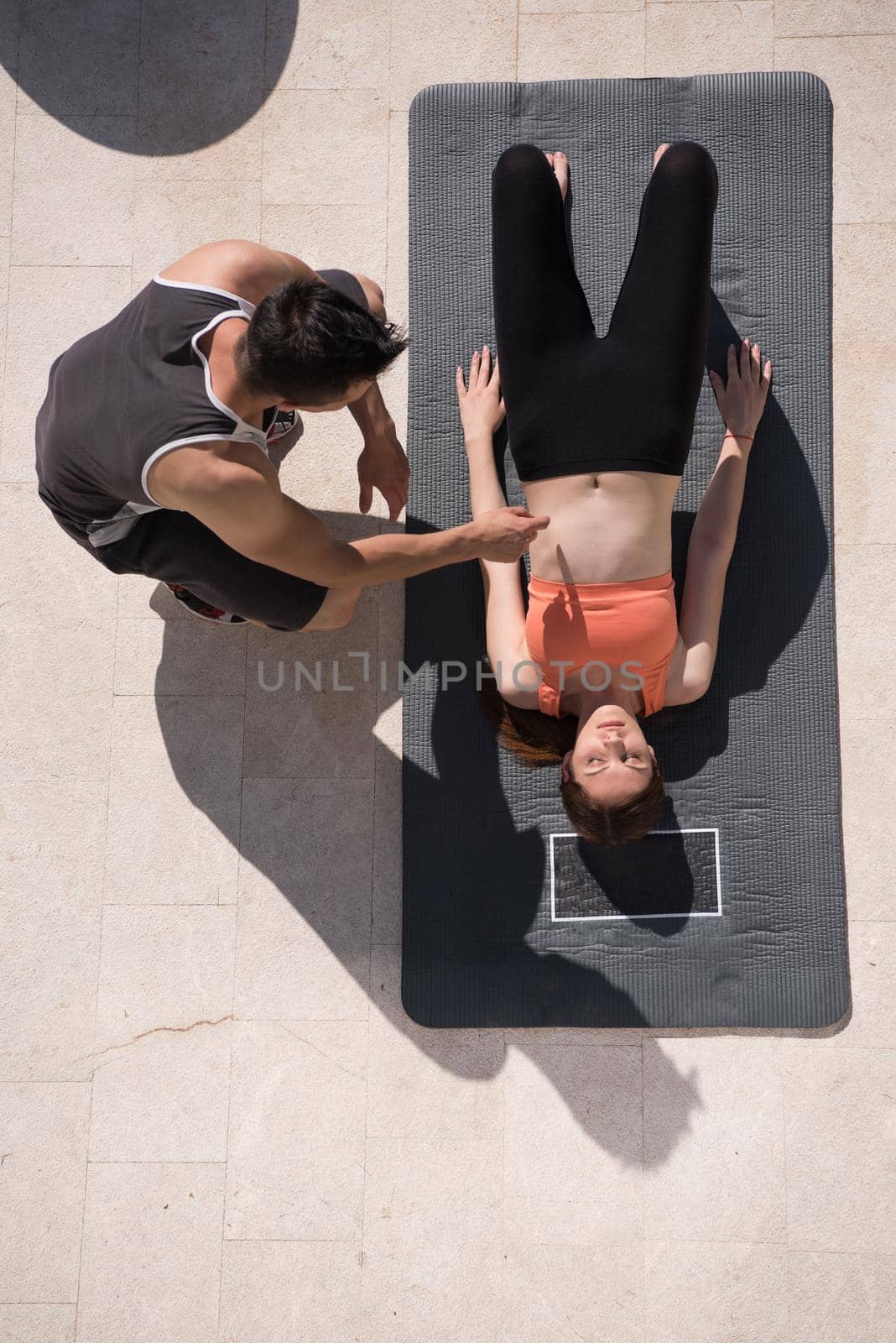 young handsome woman with personal trainer doing morning yoga exercises in front of her luxury home villa top view