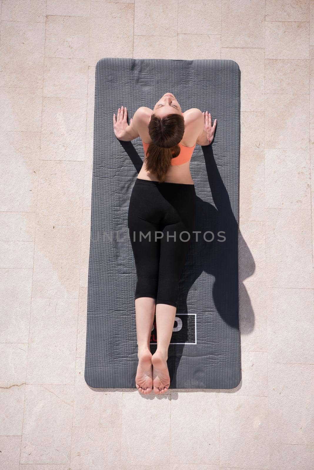 young handsome woman doing morning yoga exercises in front of her luxury home villa top view