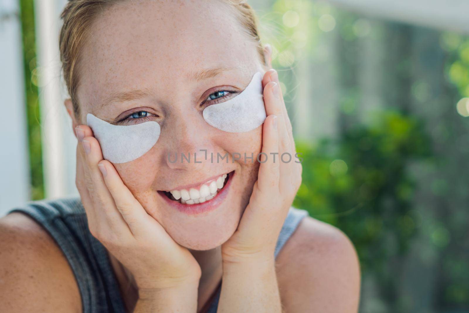 Portrait of Beauty Red-haired woman with eye patches showing an effect of perfect skin. Spa Girl.