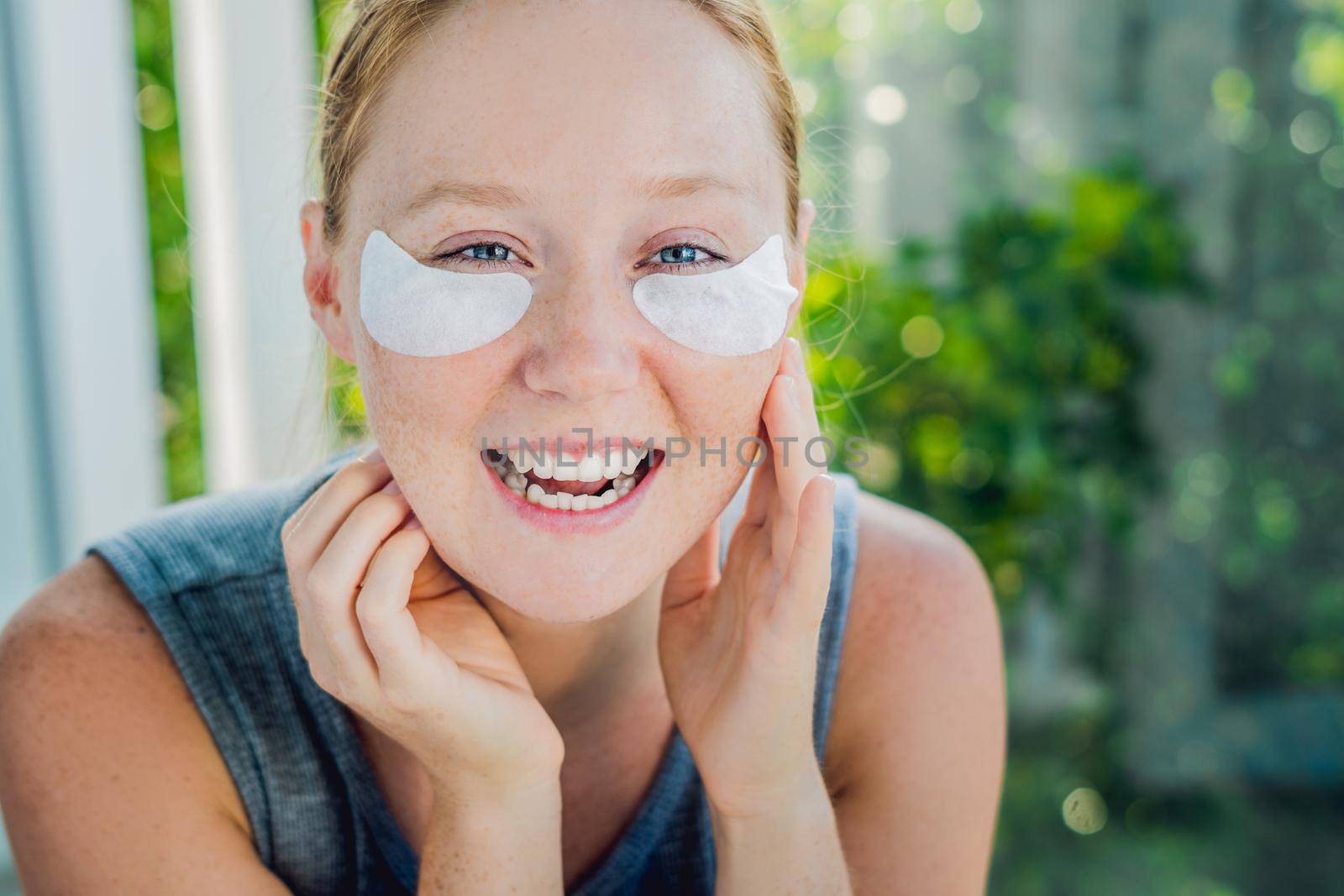 Portrait of Beauty Red-haired woman with eye patches showing an effect of perfect skin. Spa Girl.