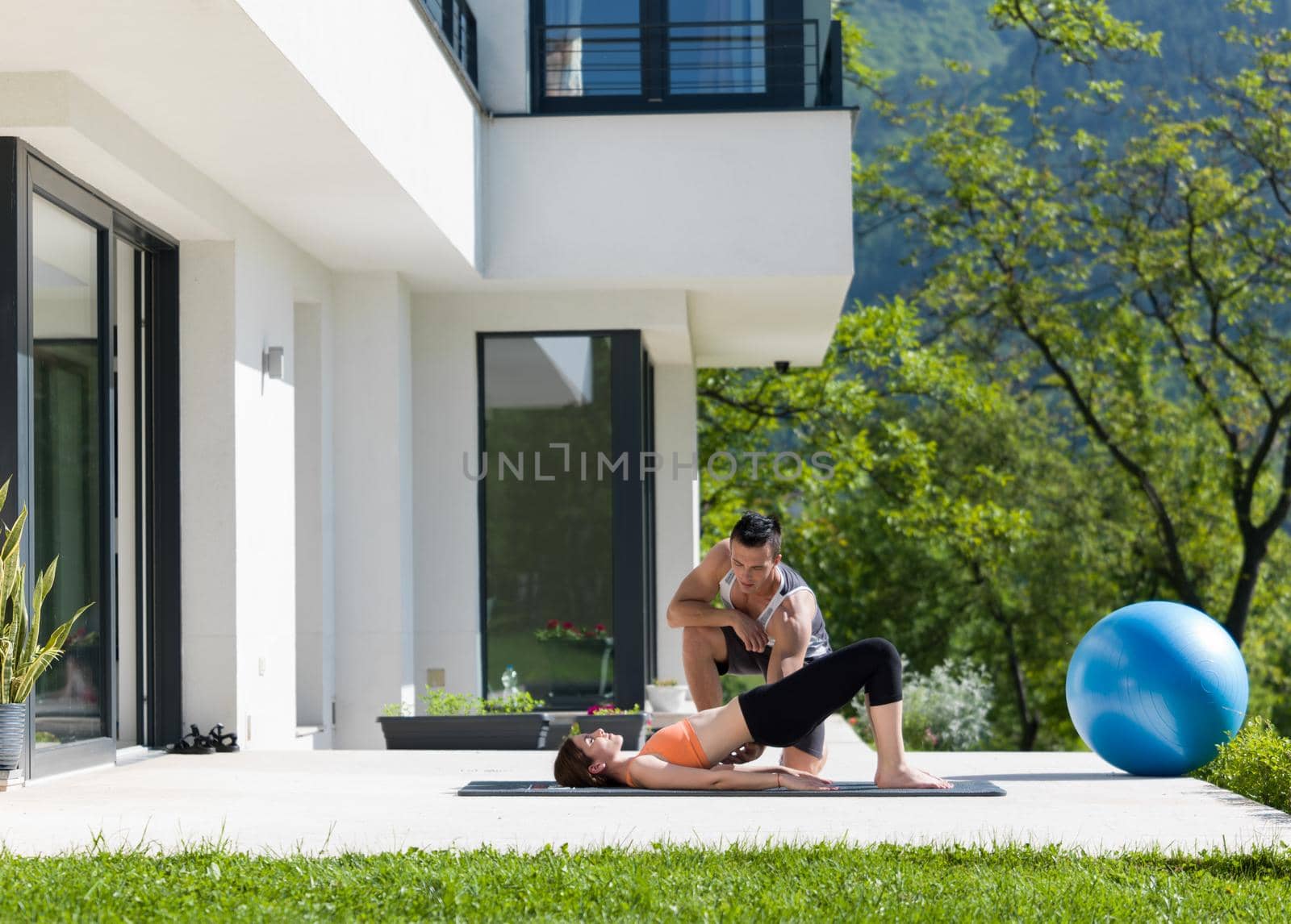 woman with personal trainer doing morning yoga exercises by dotshock