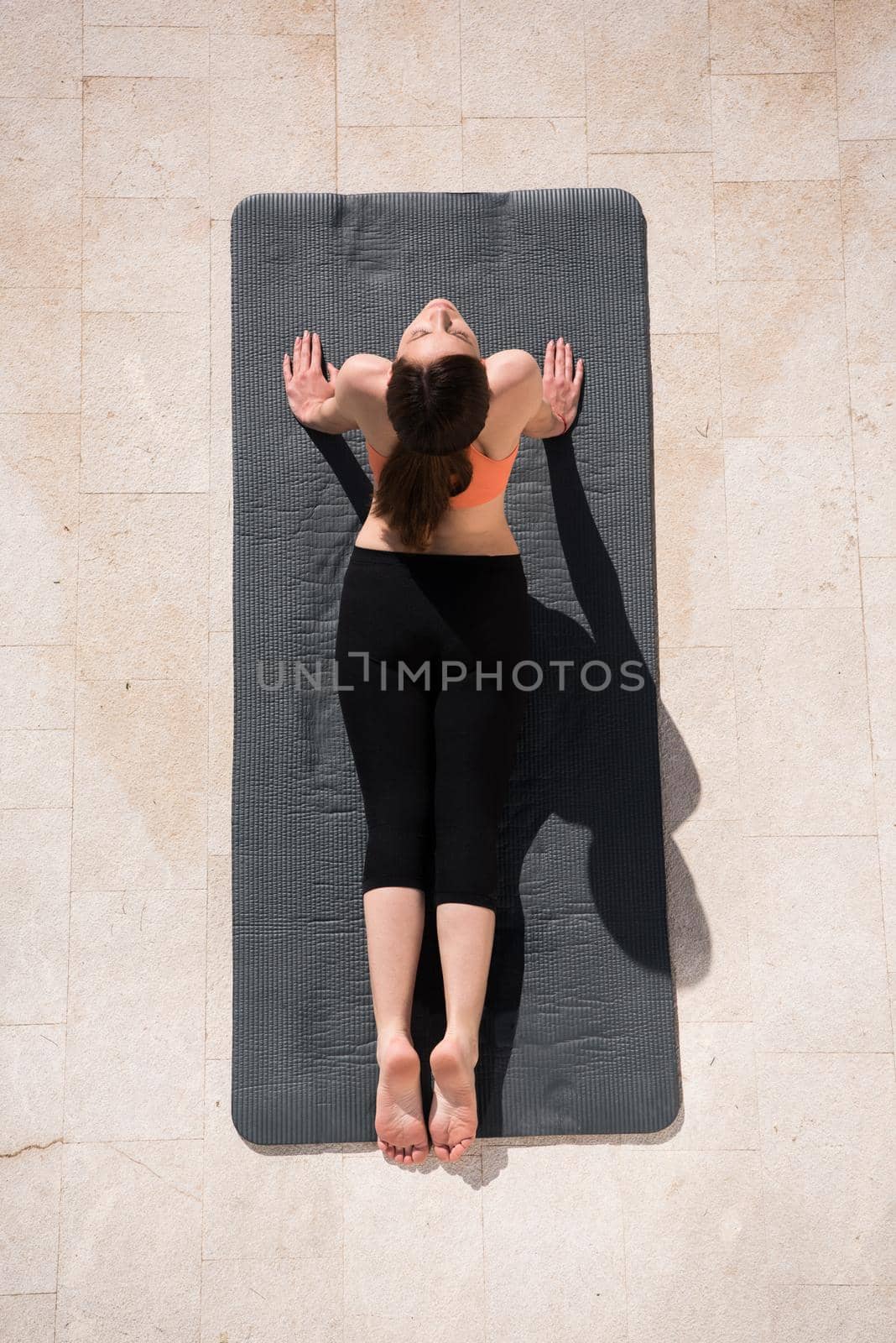 young handsome woman doing morning yoga exercises in front of her luxury home villa top view