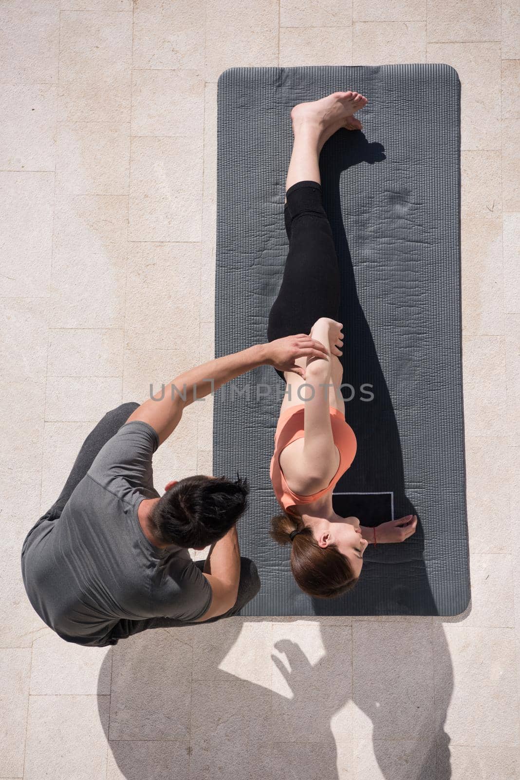 young handsome woman with personal trainer doing morning yoga exercises in front of her luxury home villa top view