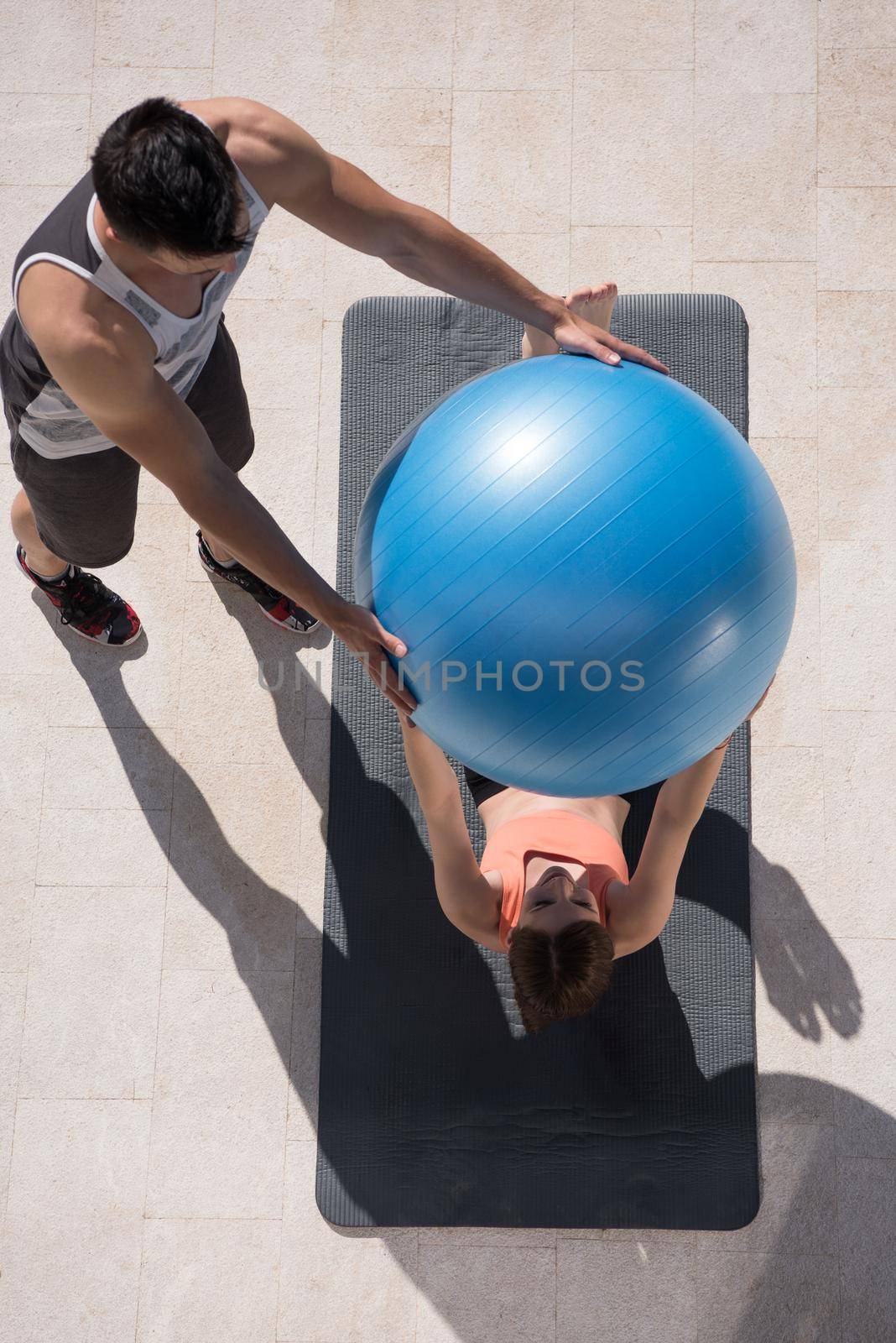 woman and personal trainer doing exercise with pilates ball by dotshock