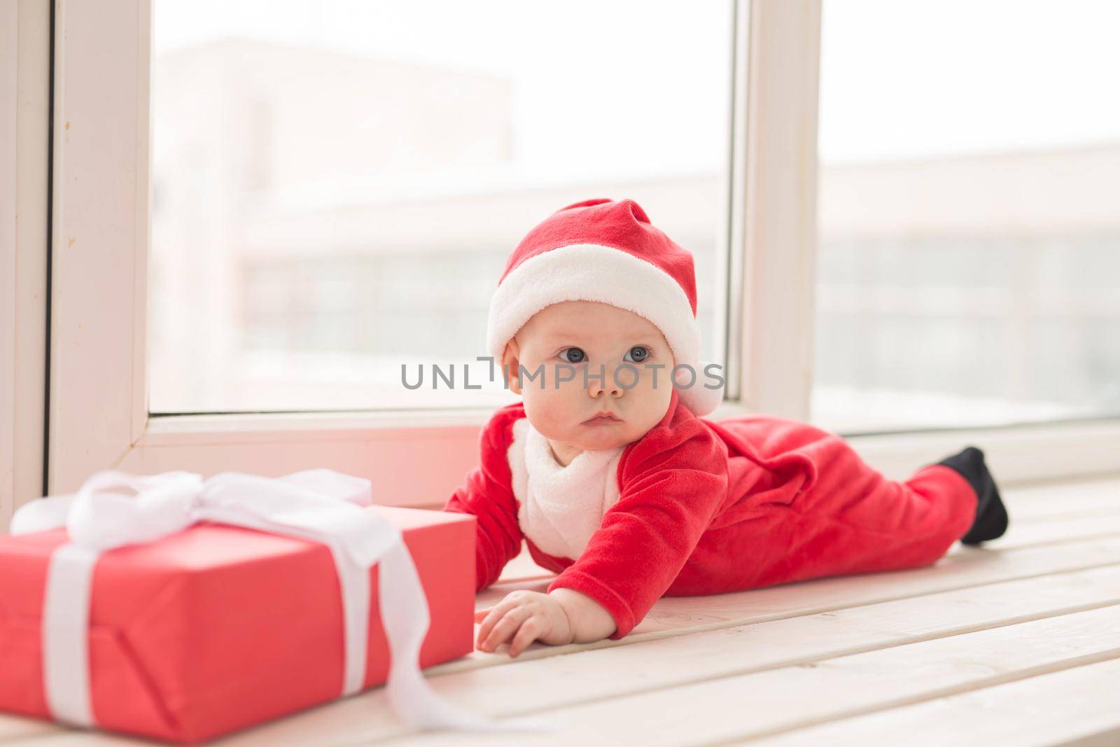 Beautiful little baby celebrates Christmas. New Year's holidays. Baby in a Christmas costume and in santa hat.