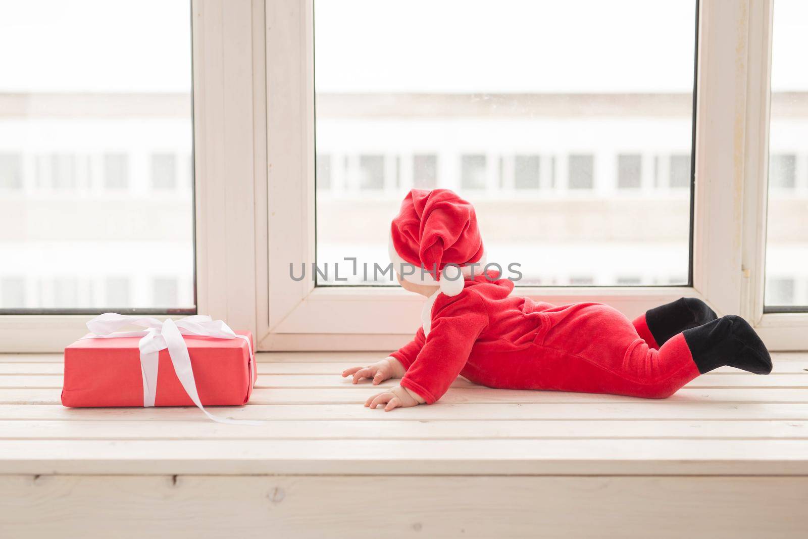 Beautiful little baby celebrates Christmas. New Year's holidays. Baby in a Christmas costume and in santa hat by Satura86