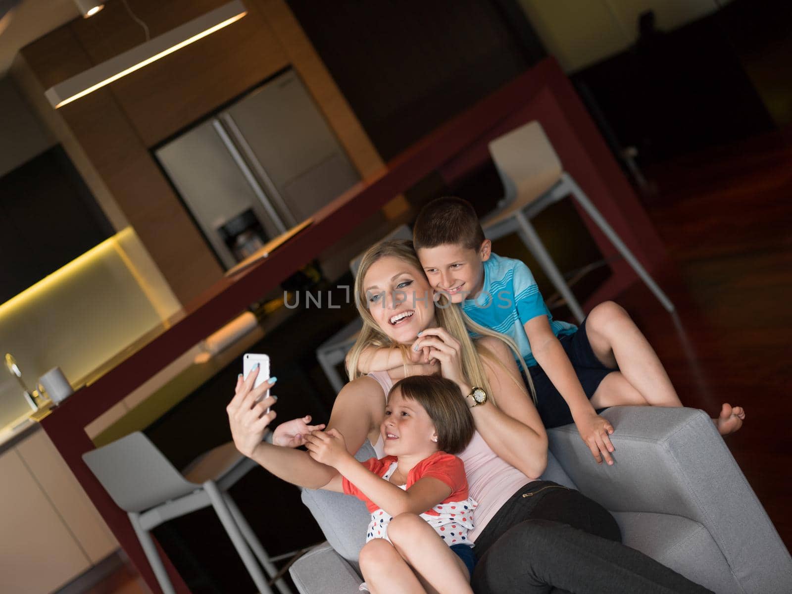 Happy family siting on sofa and using cell phone for video call  at home