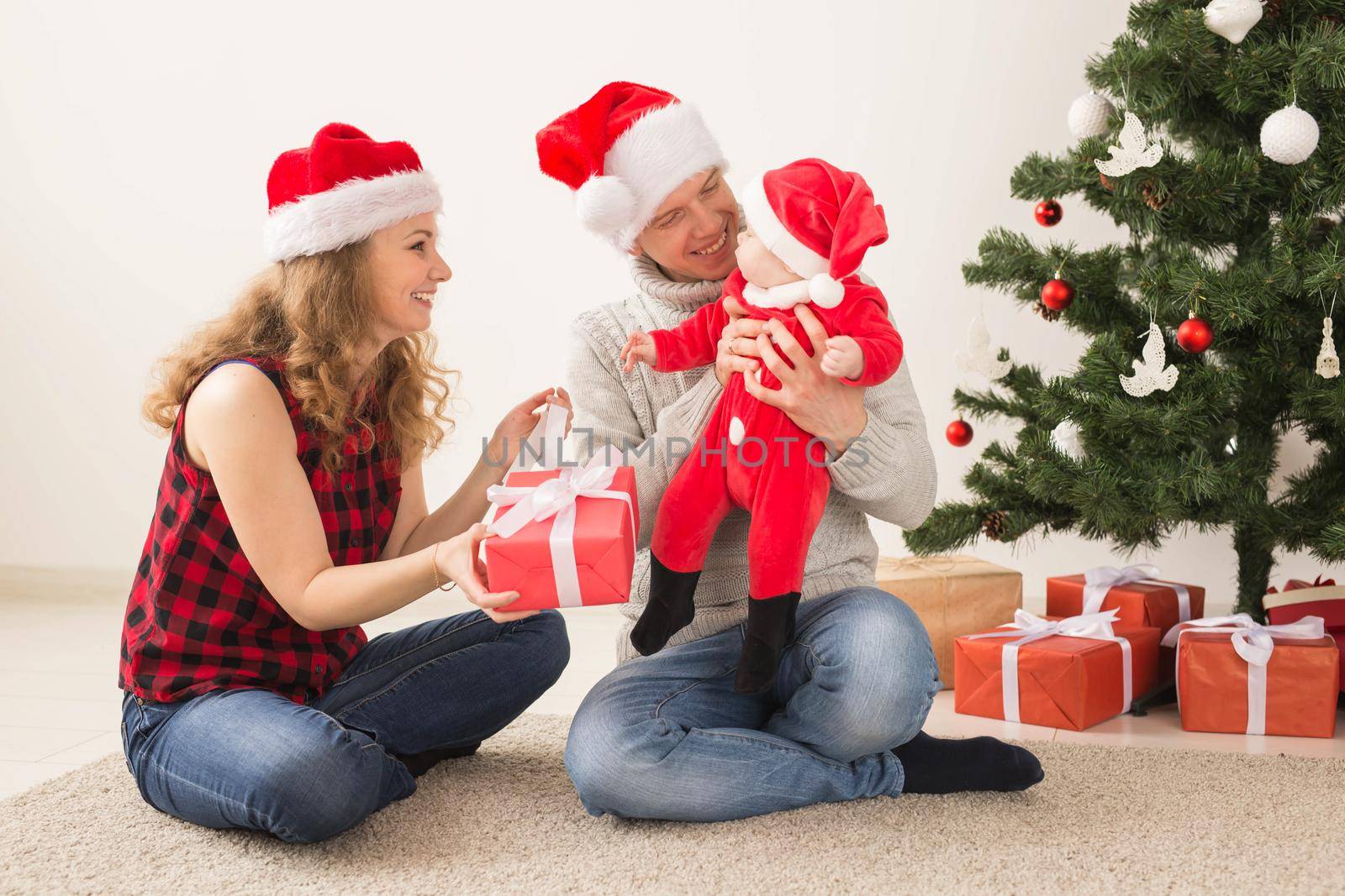 Happy couple with baby celebrating Christmas together at home. by Satura86