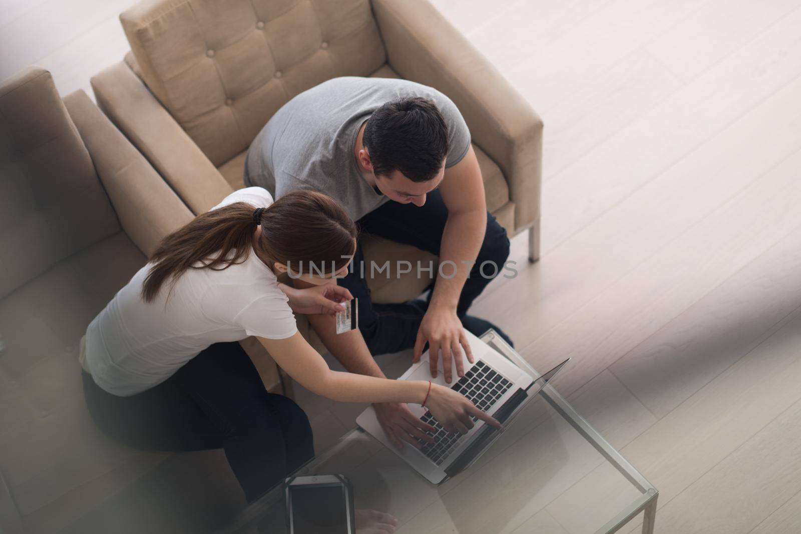 happy young couple buying online using laptop a computer and a credit card in their luxury home villa