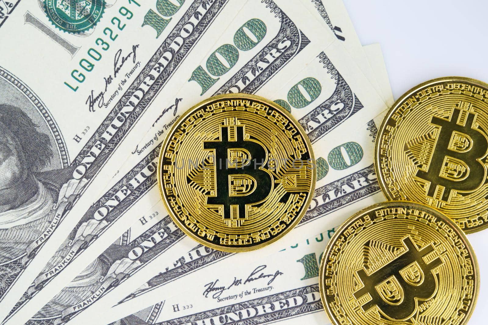 Bitcoins coin and banknotes of one hundred dollars. Close up of metal shiny bitcoin crypto currency coins and US dollar