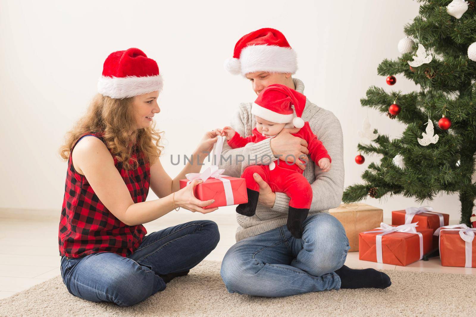 Holidays, children and family concept - Happy couple with baby celebrating Christmas together at home