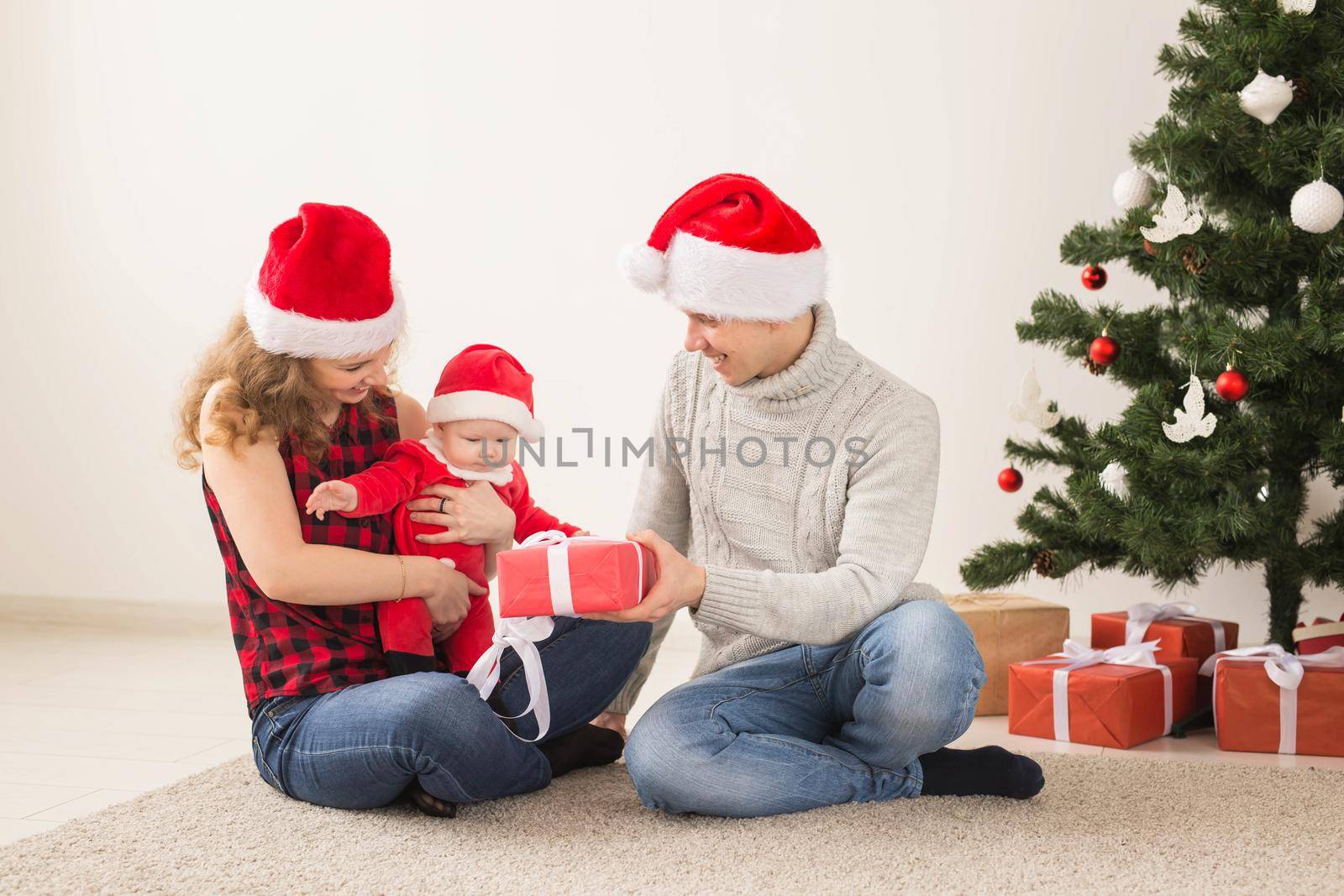 Happy couple with baby celebrating Christmas together at home. by Satura86