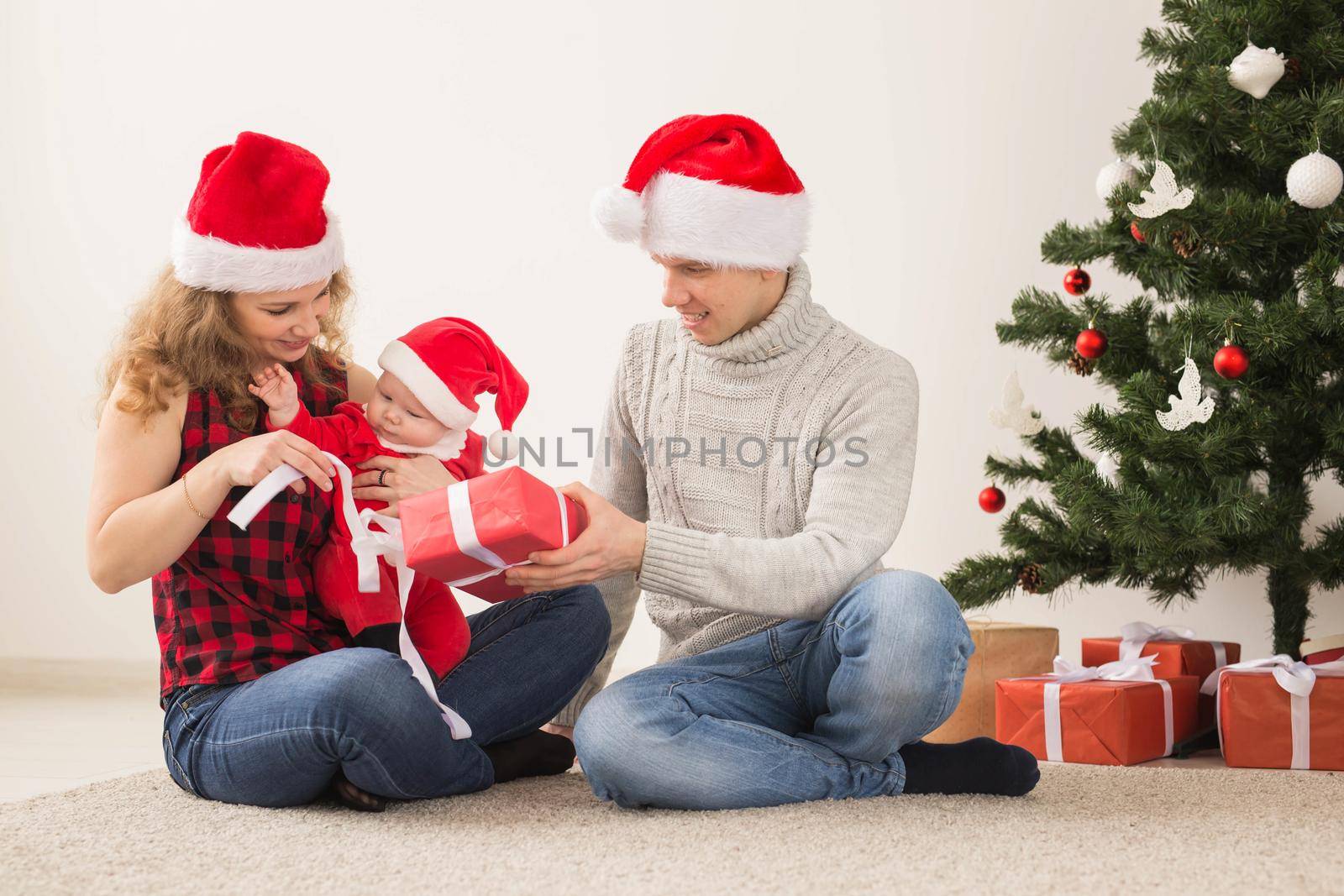 Holidays, children and family concept - Happy couple with baby celebrating Christmas together at home