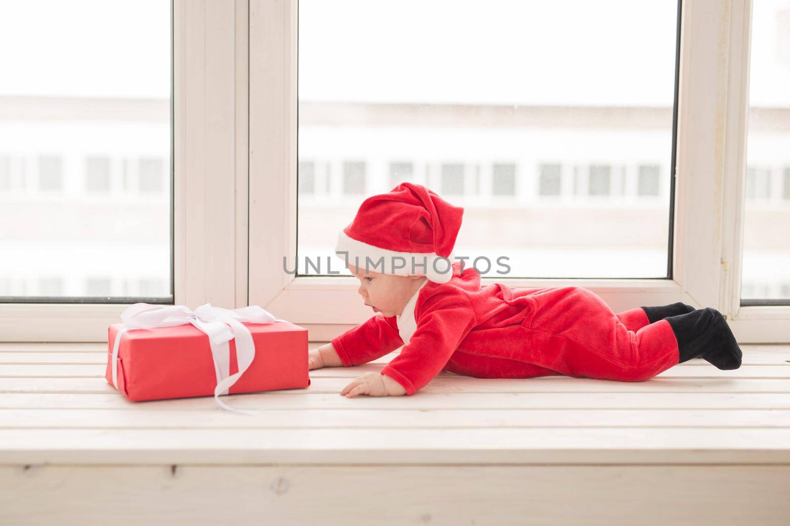 Beautiful little baby celebrates Christmas. New Year's holidays. Baby in a Christmas costume and in santa hat.