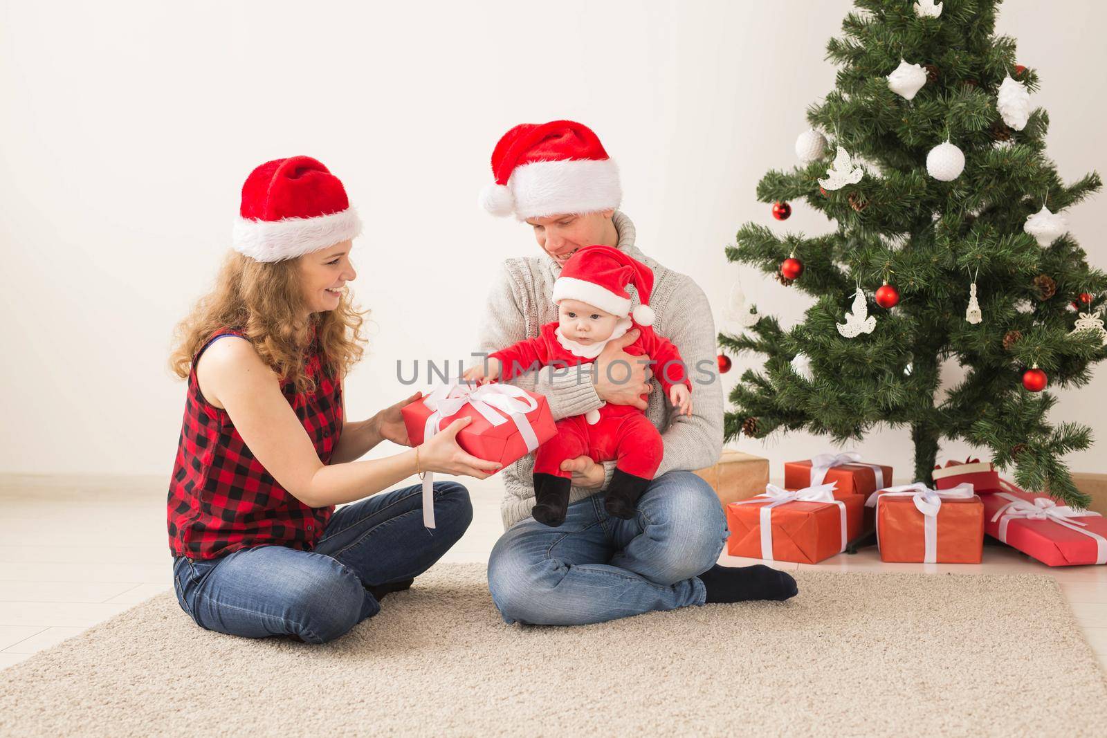 Happy couple with baby celebrating Christmas together at home