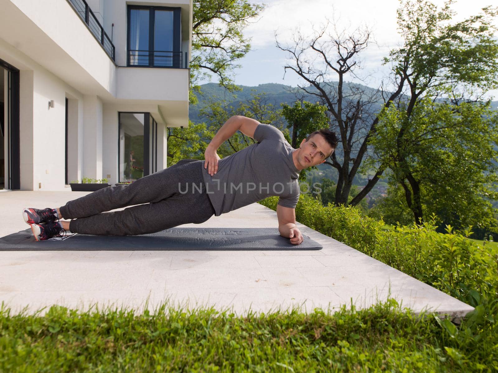 young handsome man doing morning yoga exercises in front of his luxury home villa