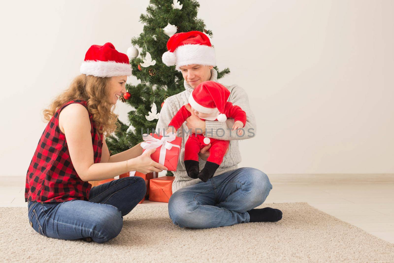 Happy couple with baby celebrating Christmas together at home