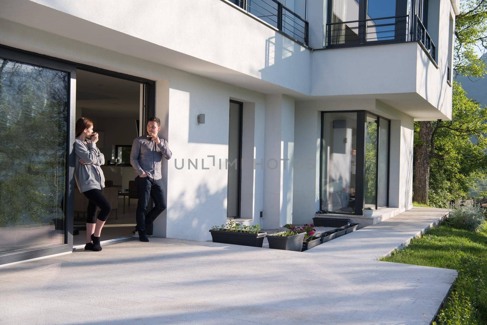 young beautiful handsome couple enjoying morning coffee on the door of their luxury home villa