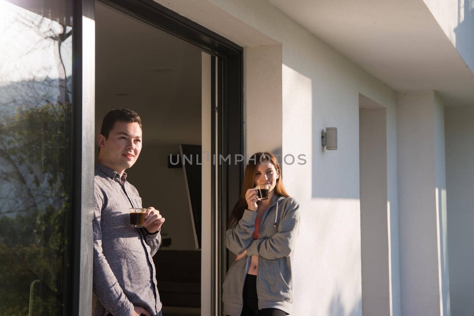 young beautiful handsome couple enjoying morning coffee on the door of their luxury home villa