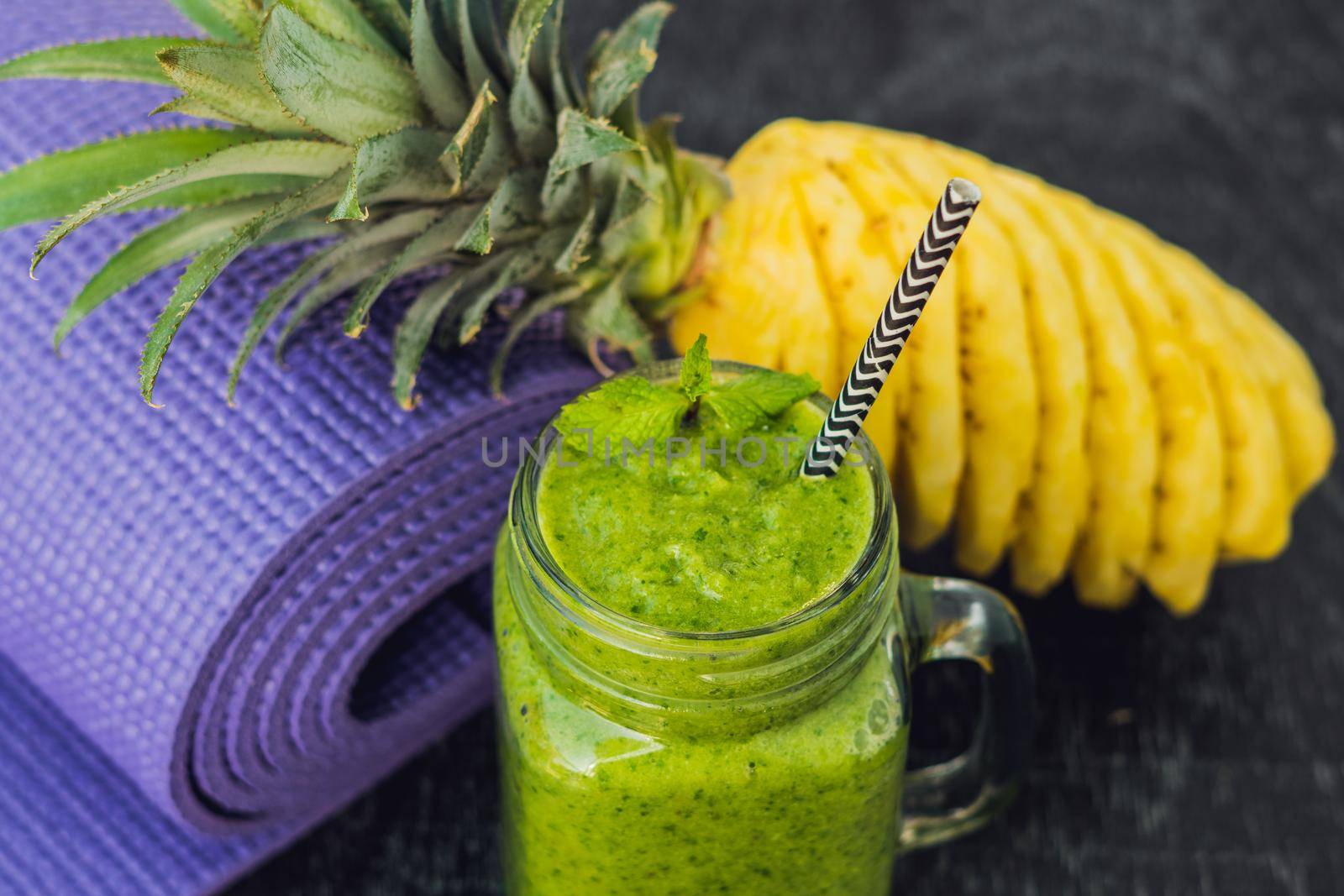 Green smoothies made of spinach and pineapple and a yoga mat. Healthy eating and sports concept by galitskaya