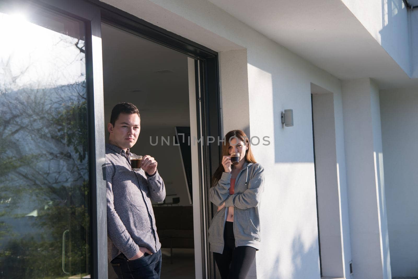 young beautiful handsome couple enjoying morning coffee on the door of their luxury home villa