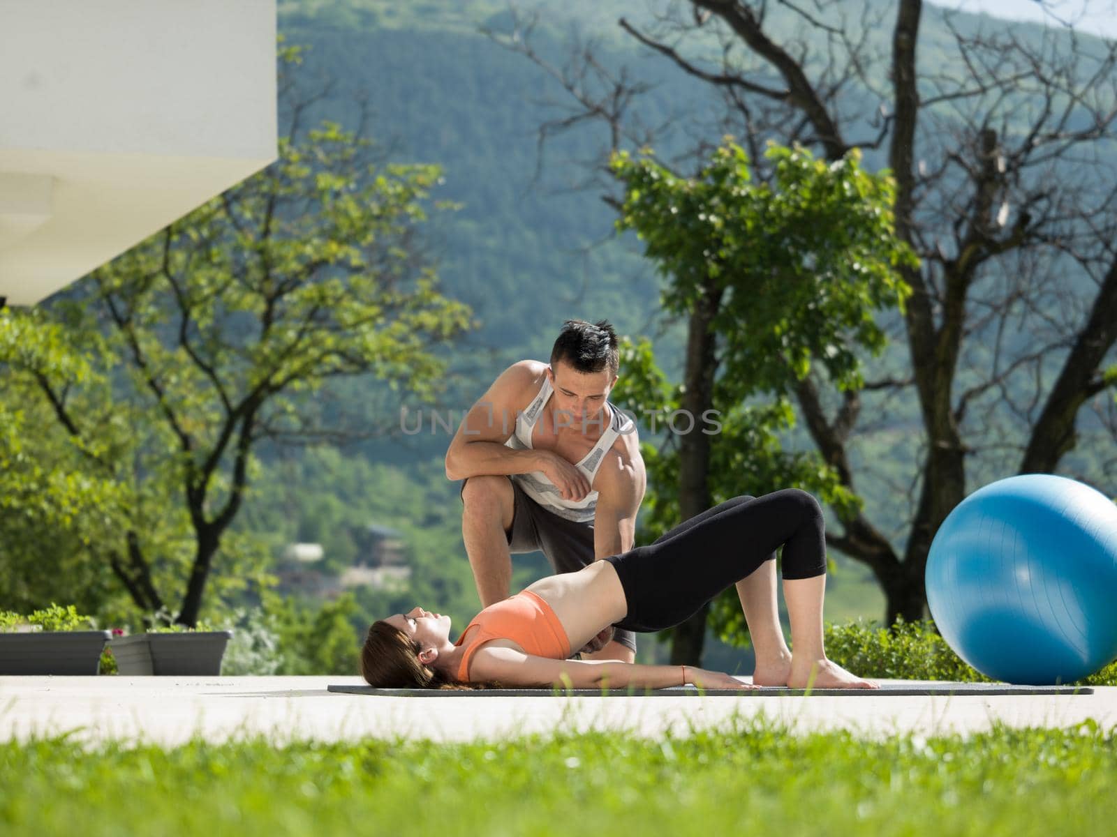 young handsome woman with personal trainer doing morning yoga exercises in front of her luxury home villa