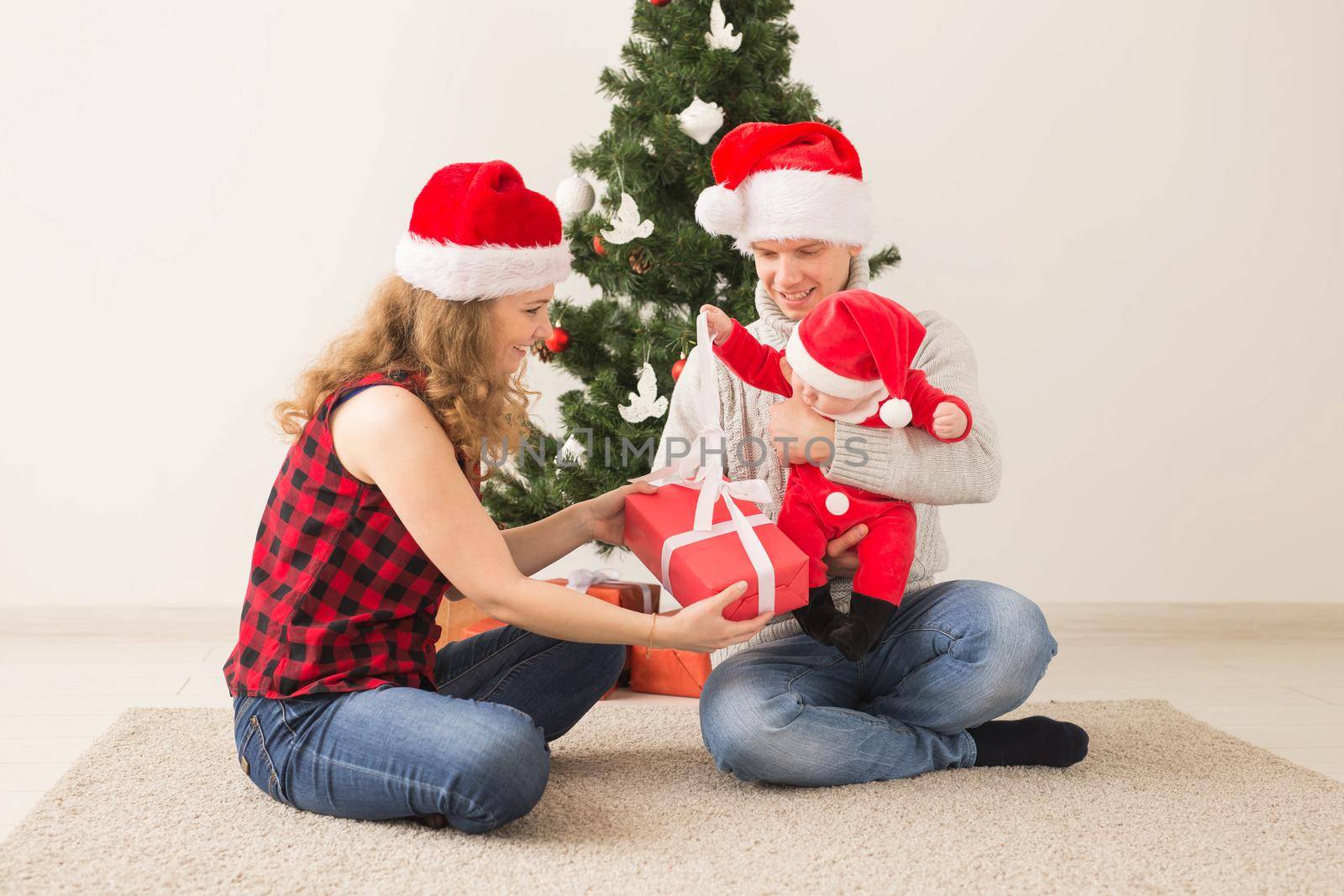 Happy couple with baby celebrating Christmas together at home