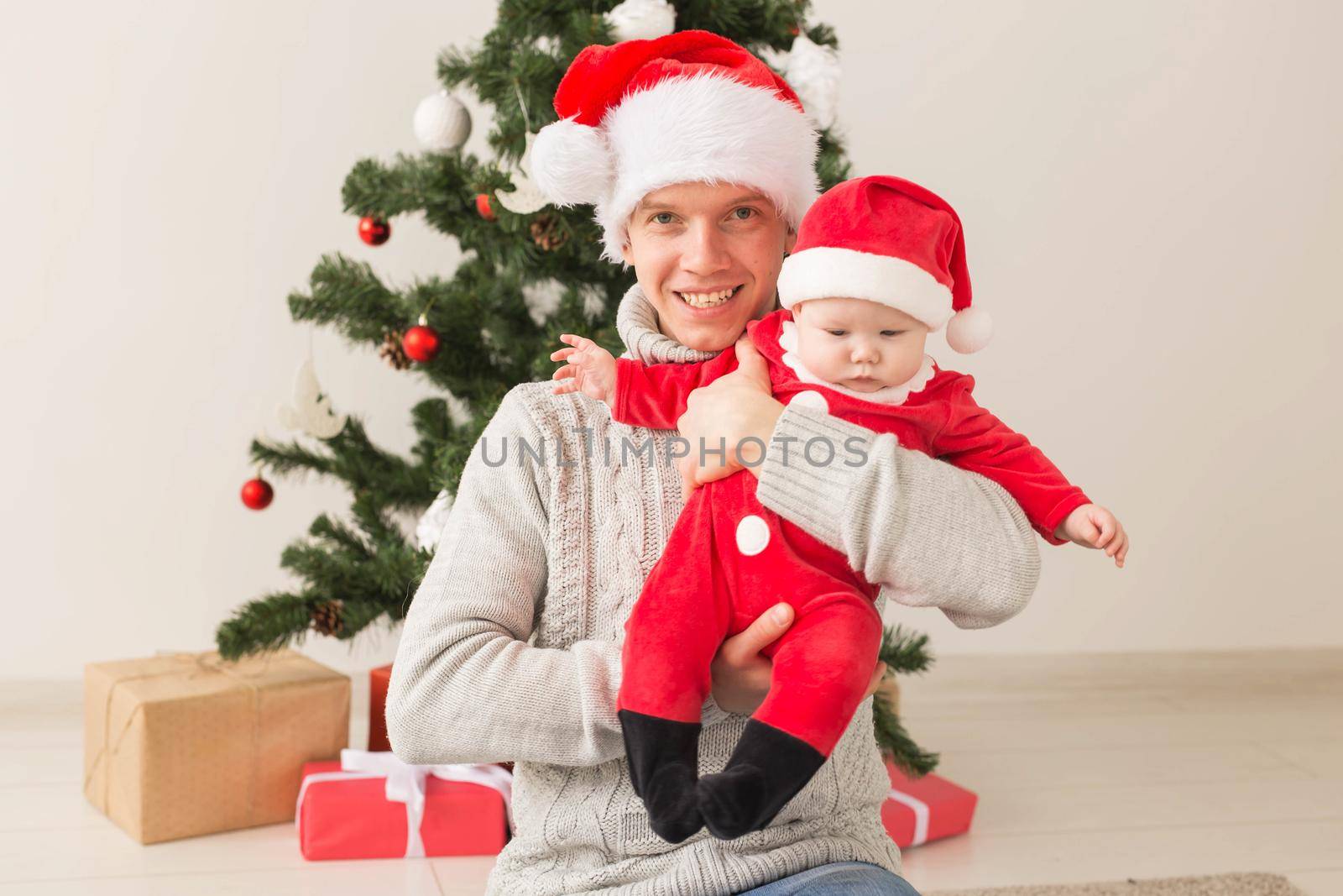 Father with his baby boy wearing Santa hats celebrating Christmas. by Satura86