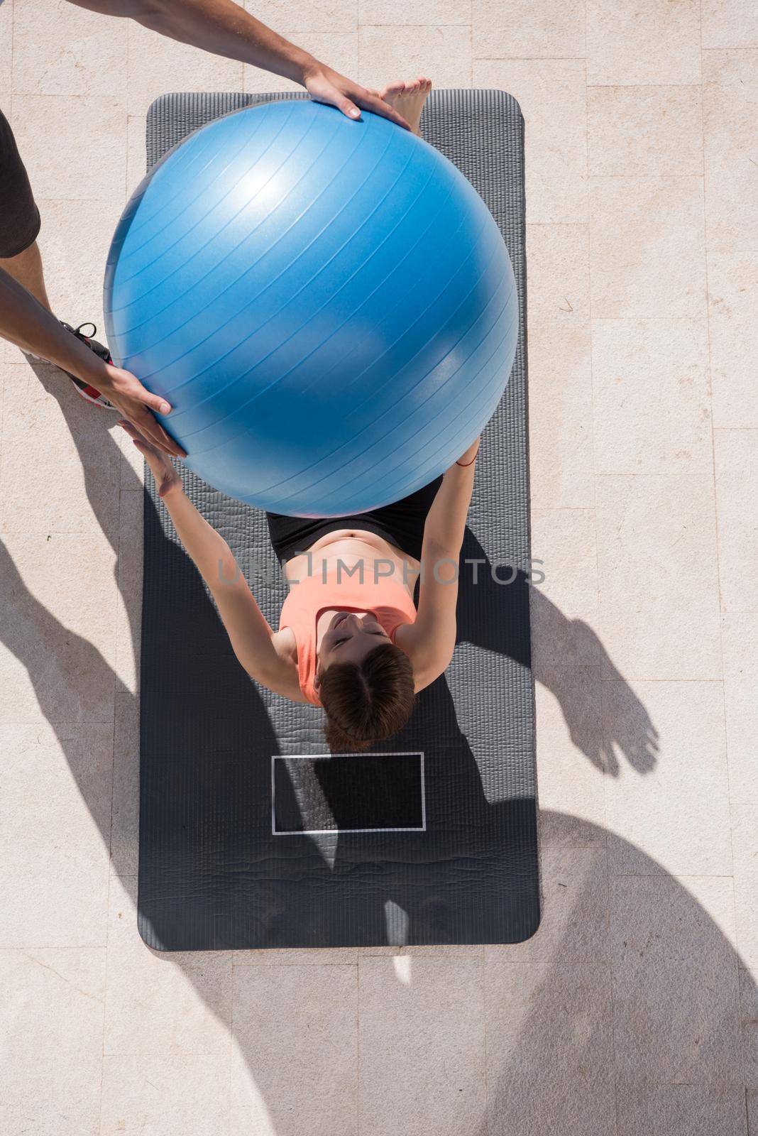 young beautiful woman and personal trainer doing exercise with pilates ball in front of her luxury home