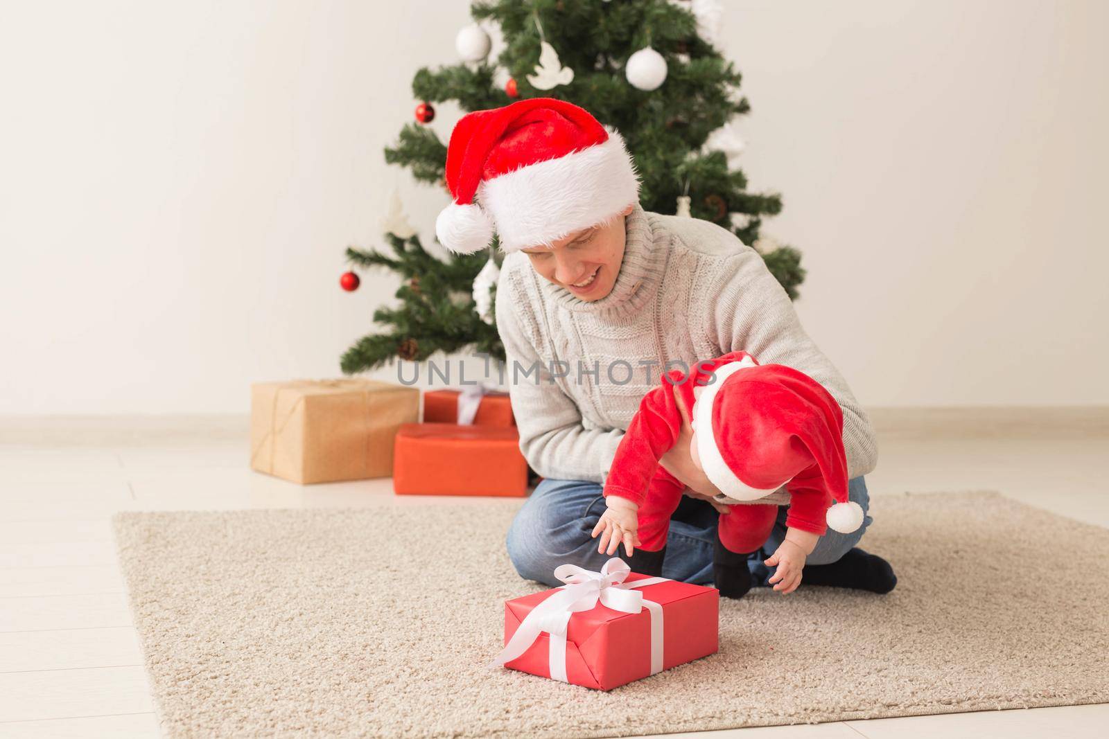 Father with his baby boy wearing Santa hats celebrating Christmas. by Satura86